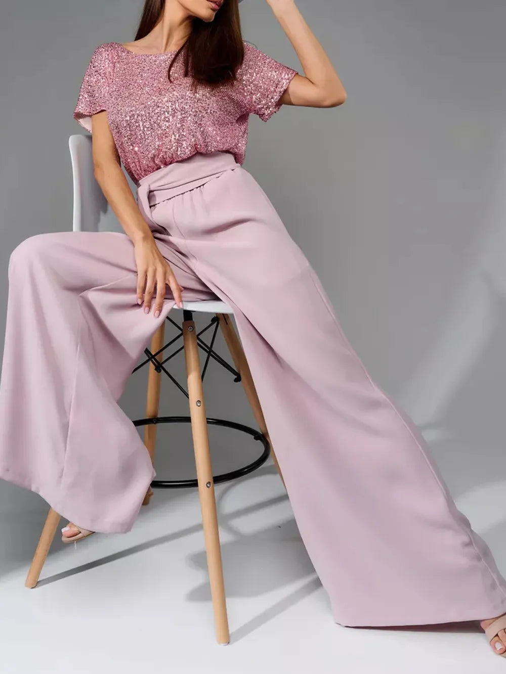 Dusty pink sequin short-sleeve jumpsuit with gathered waist and wide-leg trousers.