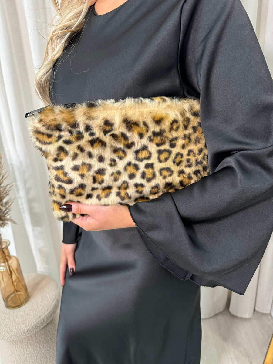 "Model holding a stylish faux fur leopard print handbag, perfect for any occasion."
