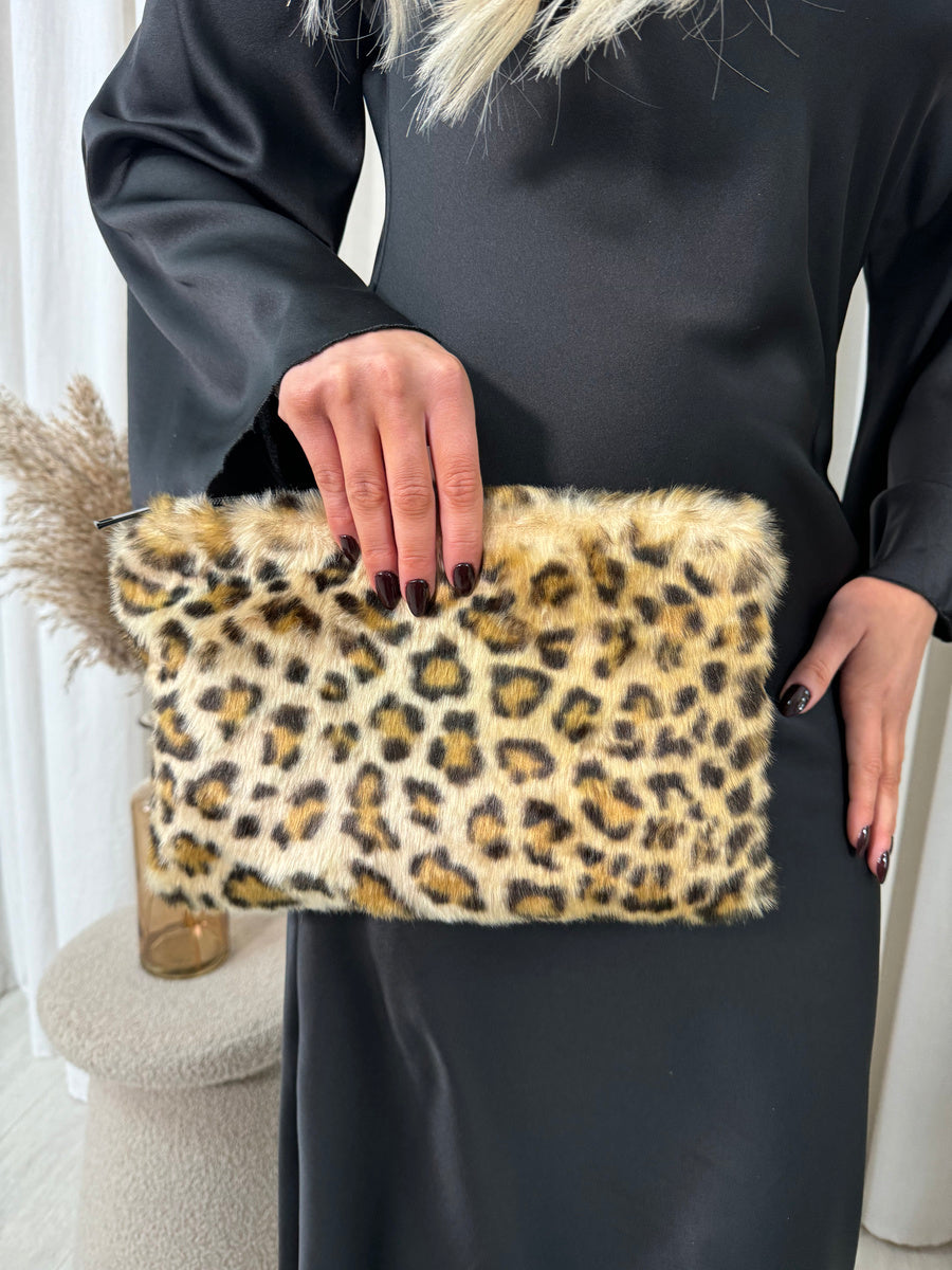 "Model holding a stylish faux fur leopard print handbag, perfect for any occasion."