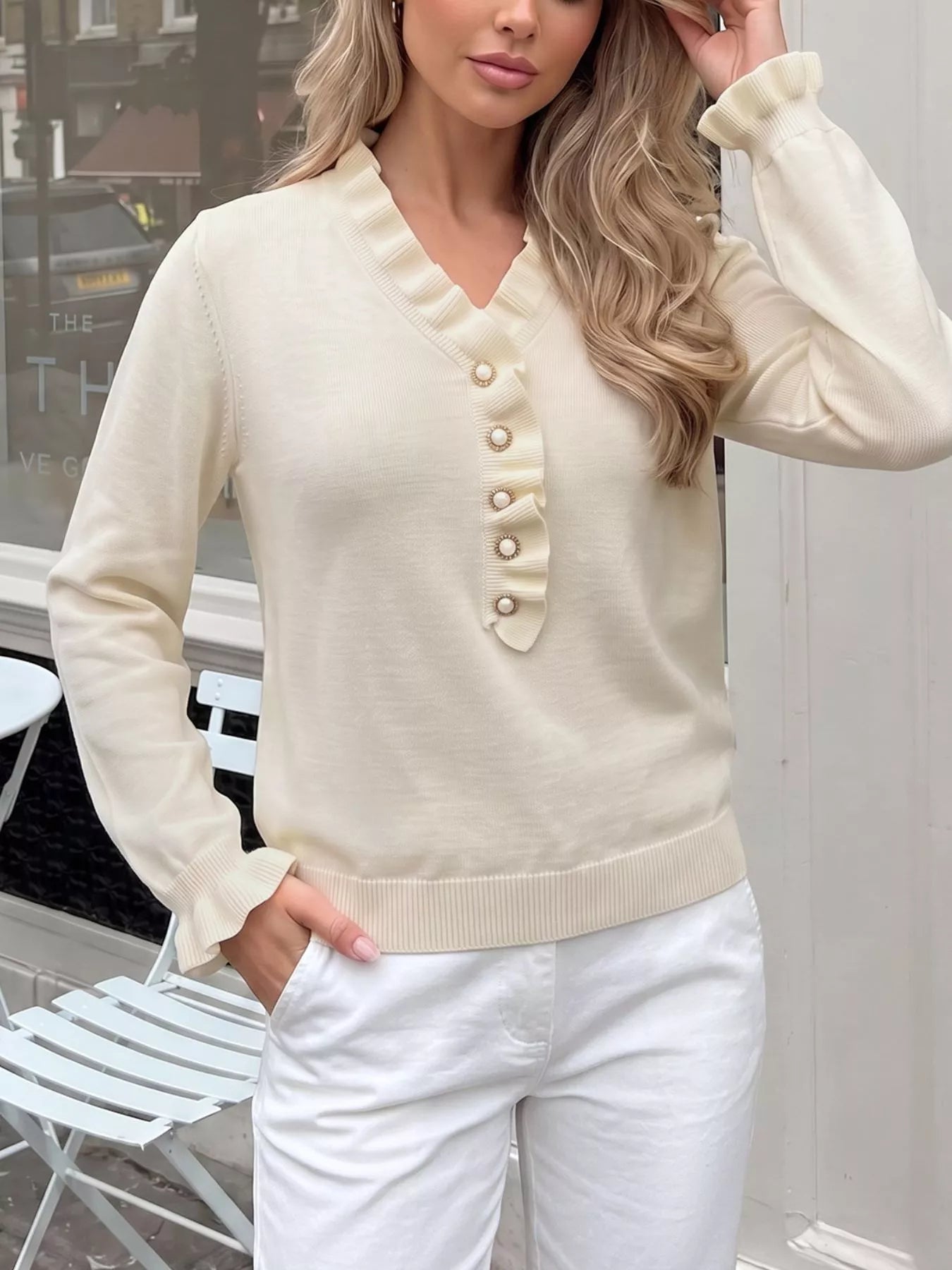 Cream knit V-neck sweater with ruffle trim and pearl-look button placket