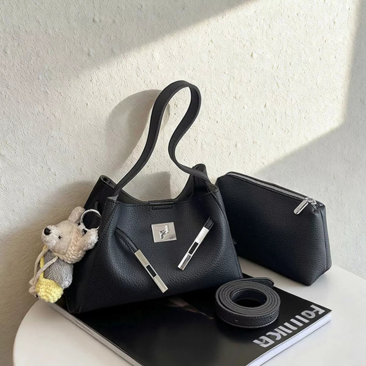 Black lock-detail crossbody bag with adjustable strap, silver front hardware, and zip top