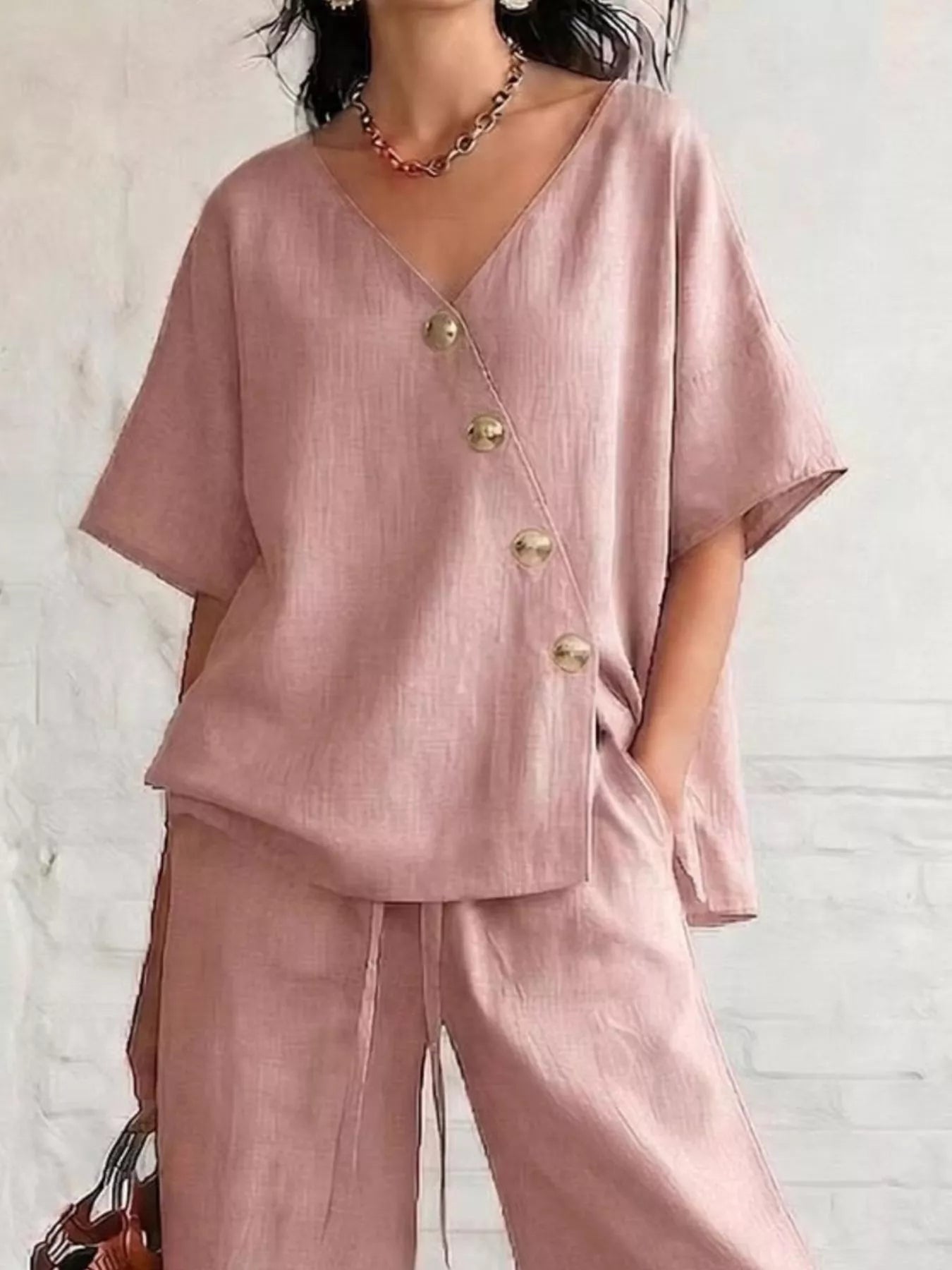 Pink surplice button-front half-sleeve top with gold buttons and wide-leg pants
