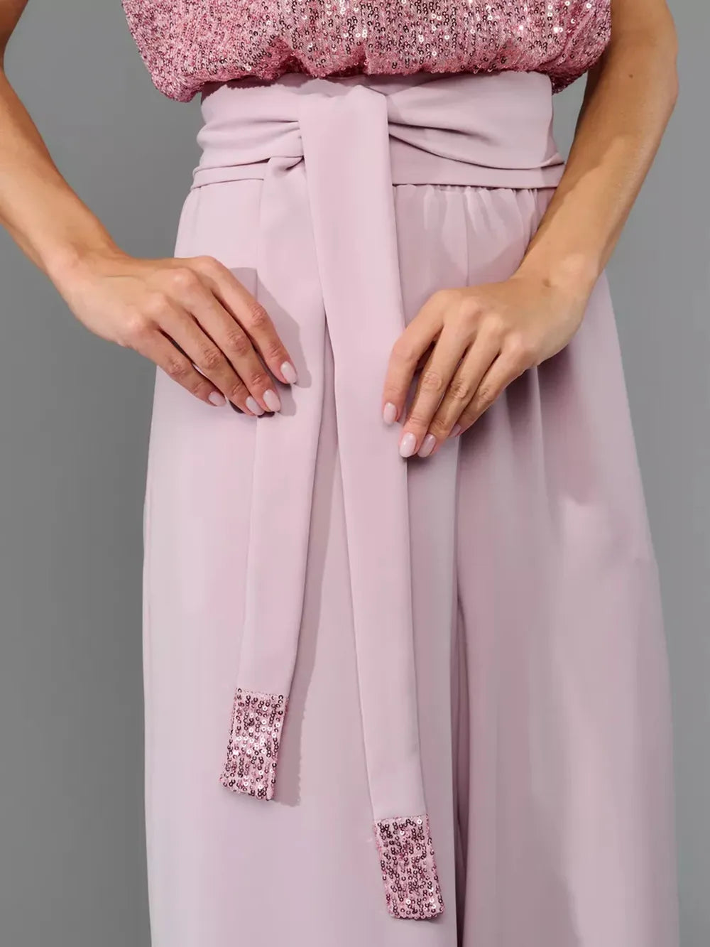 Dusty pink wide-leg jumpsuit close-up of pleated waist and matching fabric ties.