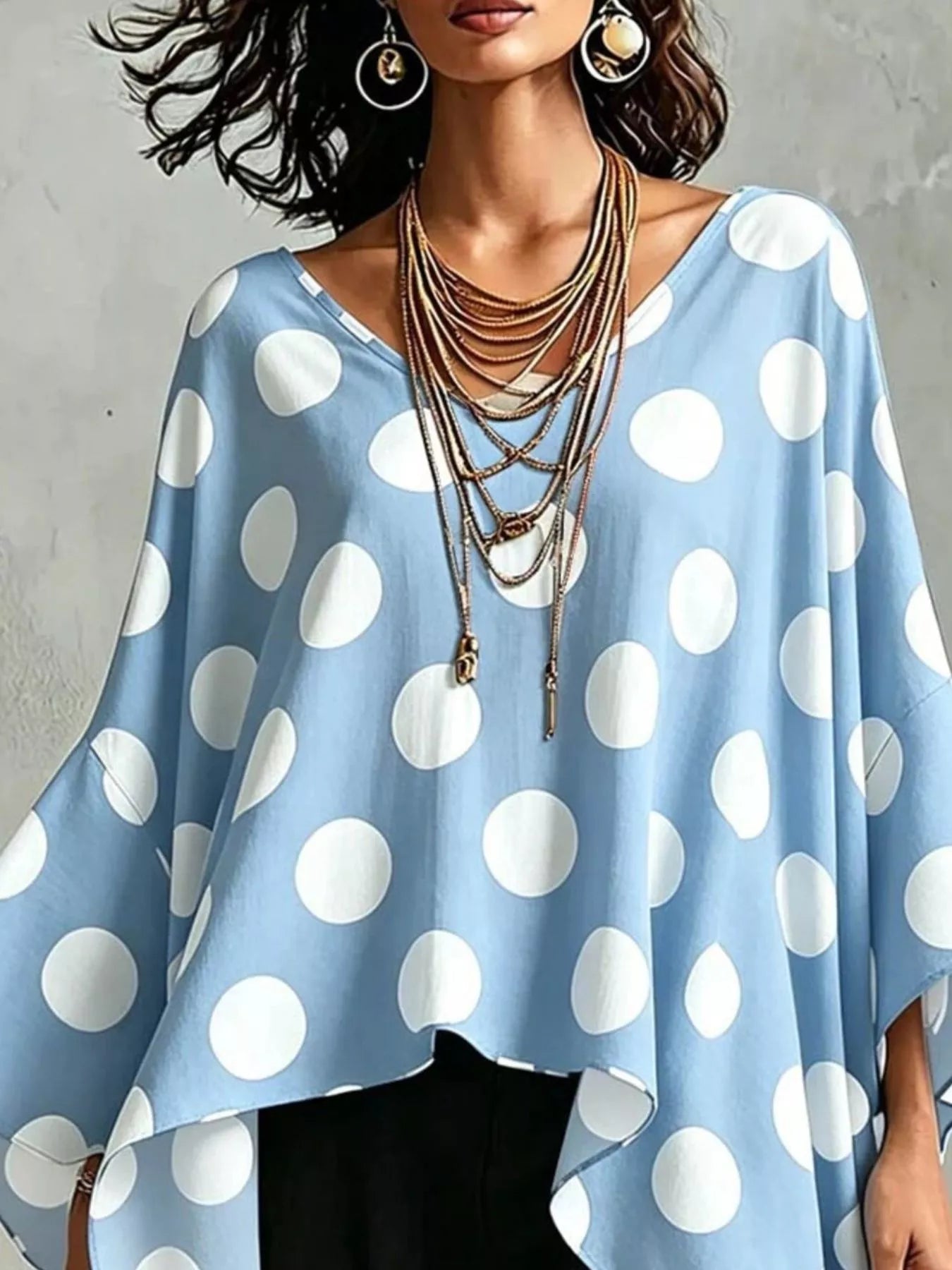 Light blue polka dot asymmetrical hem blouse with wide neckline and relaxed fit.