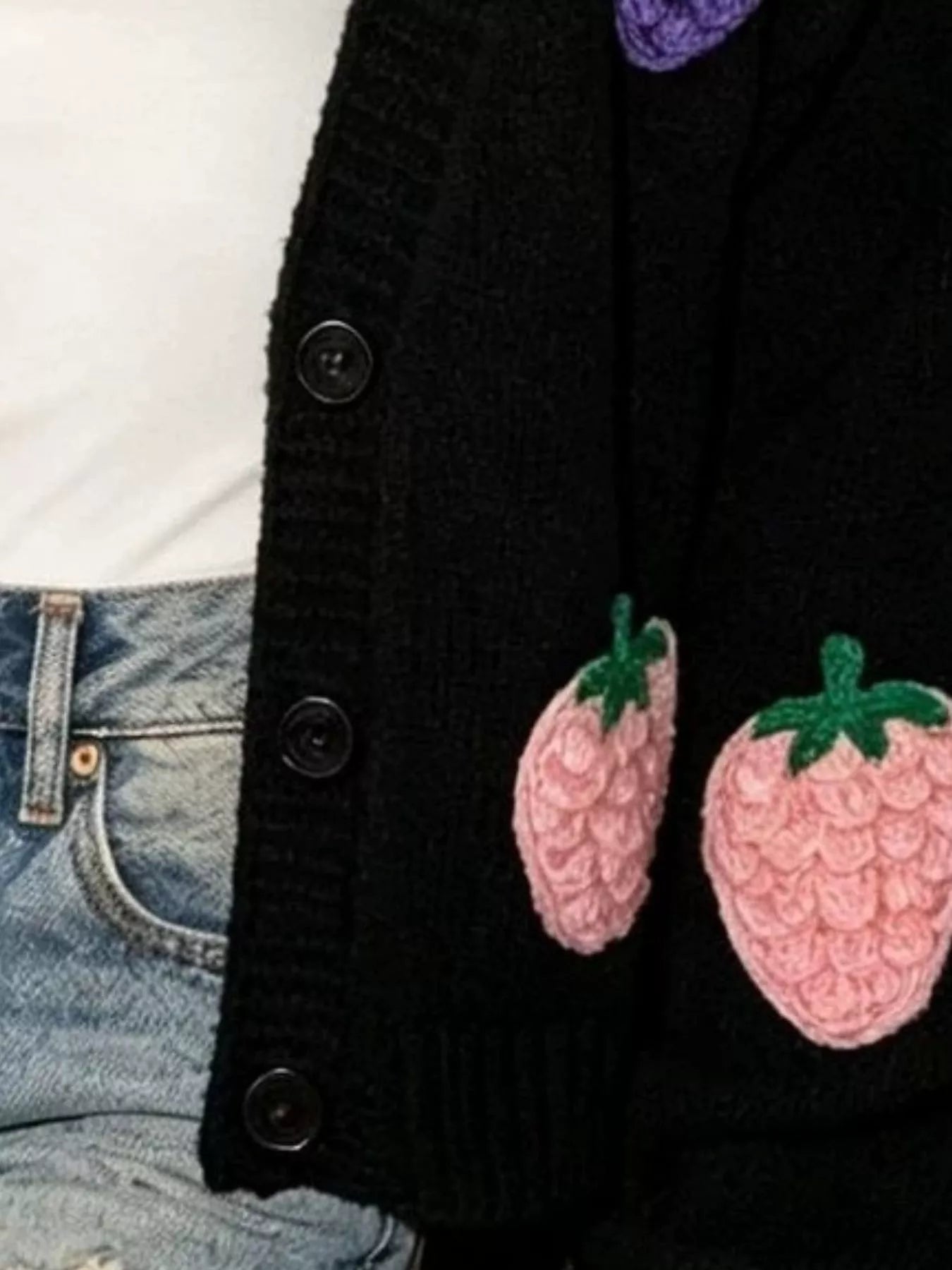 Black knit cardigan close-up: fruit applique patches on button-front