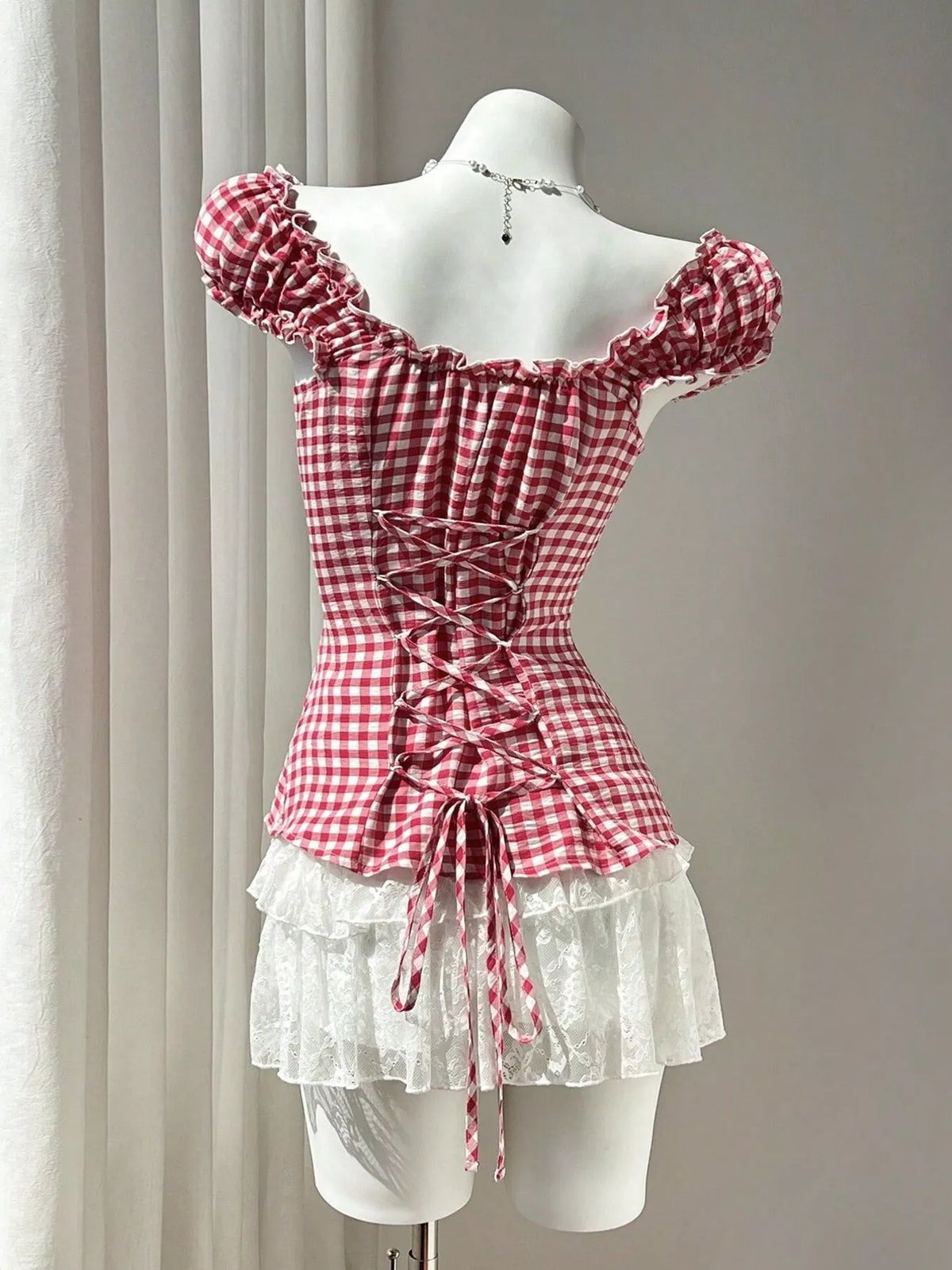 Red gingham blouse with cap sleeves, center-back lace-up, and ruffled peplum hem