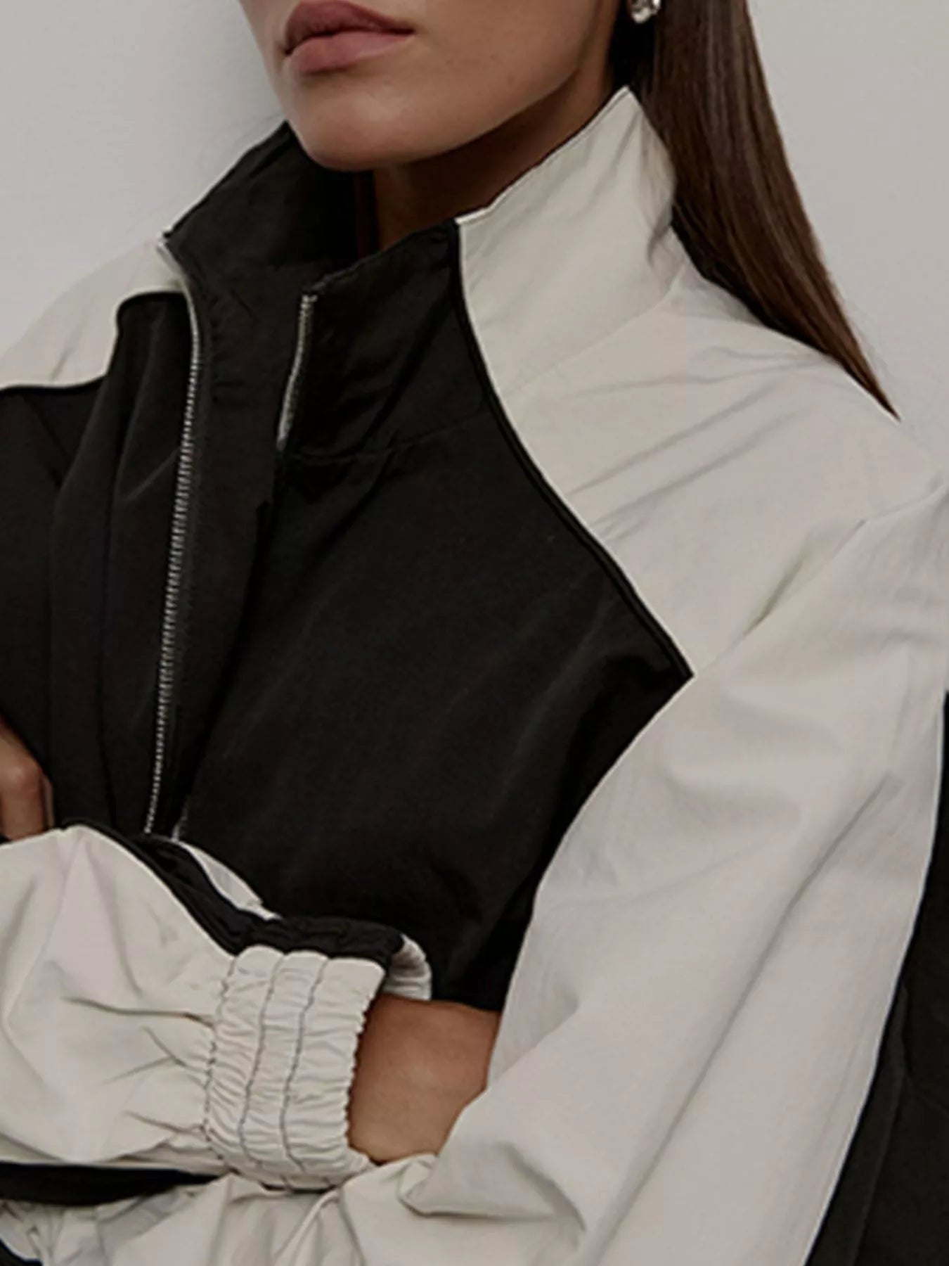 Color-block zip-up jacket with black-and-white panels and visible front zipper.