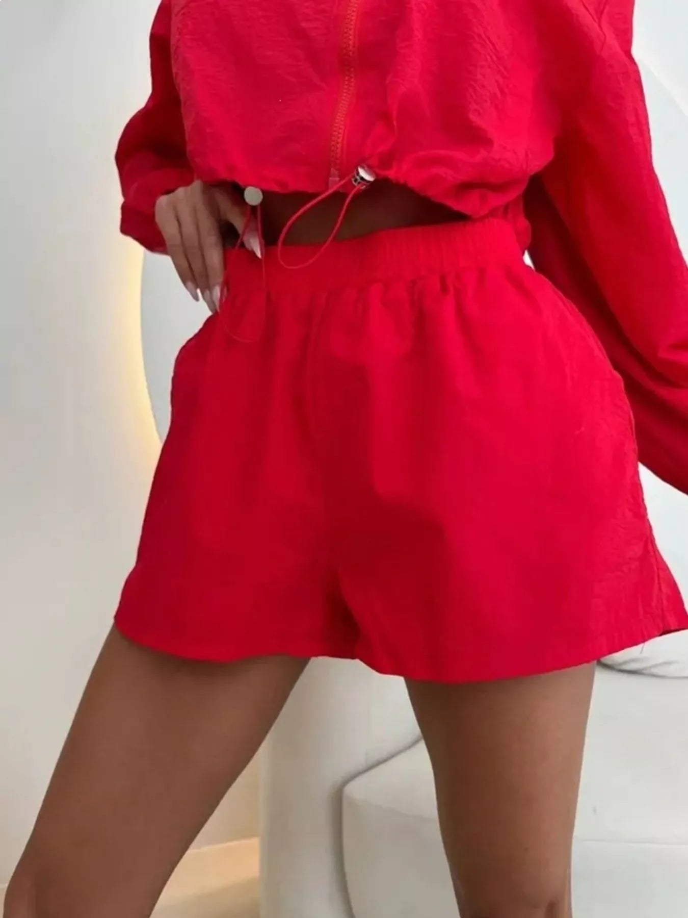 Red zip-up jacket and shorts set, close-up zipper front and drawstring waist