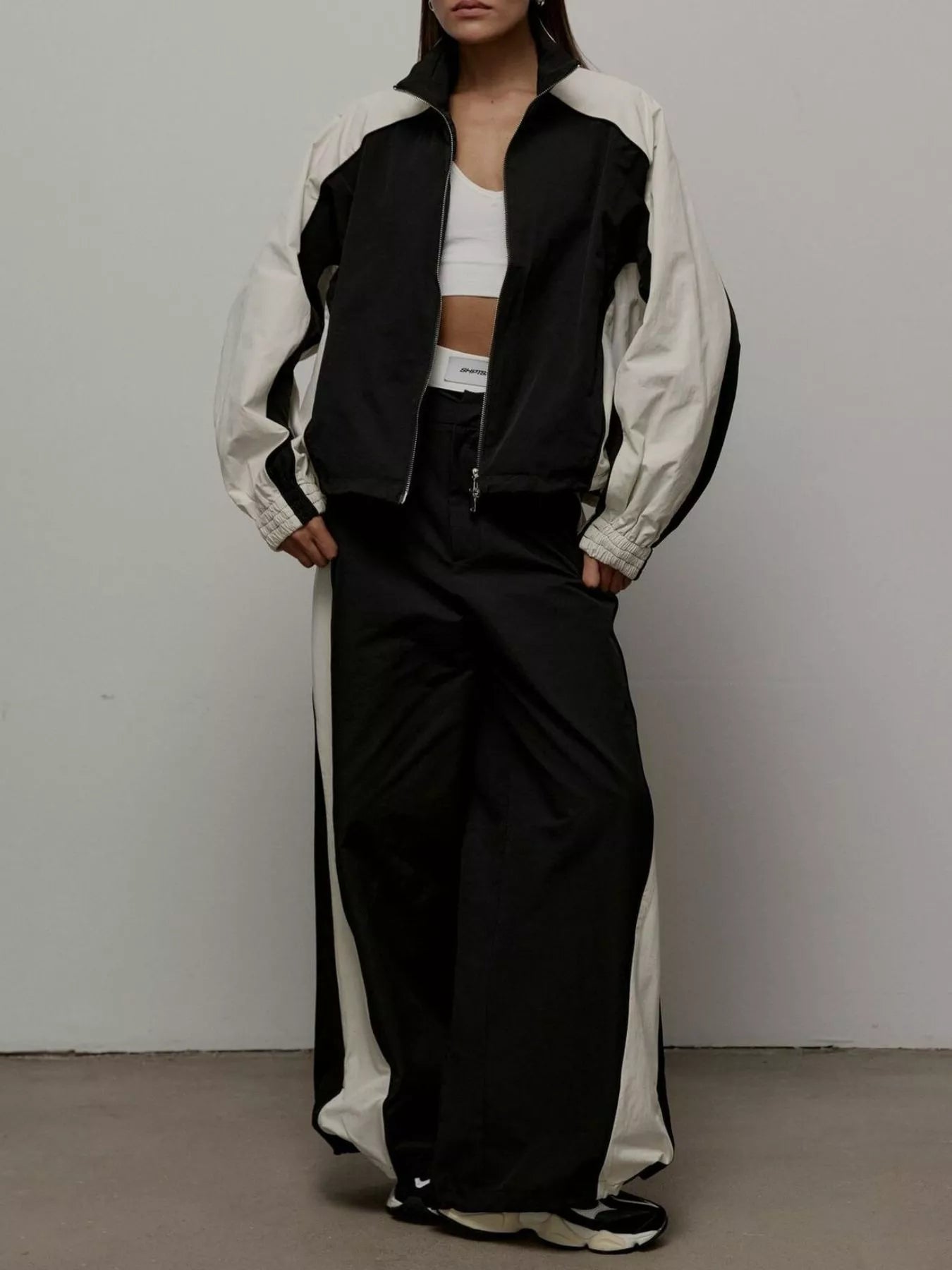 Color-block zip-up jacket and wide-leg pants set in black and light contrast panels.