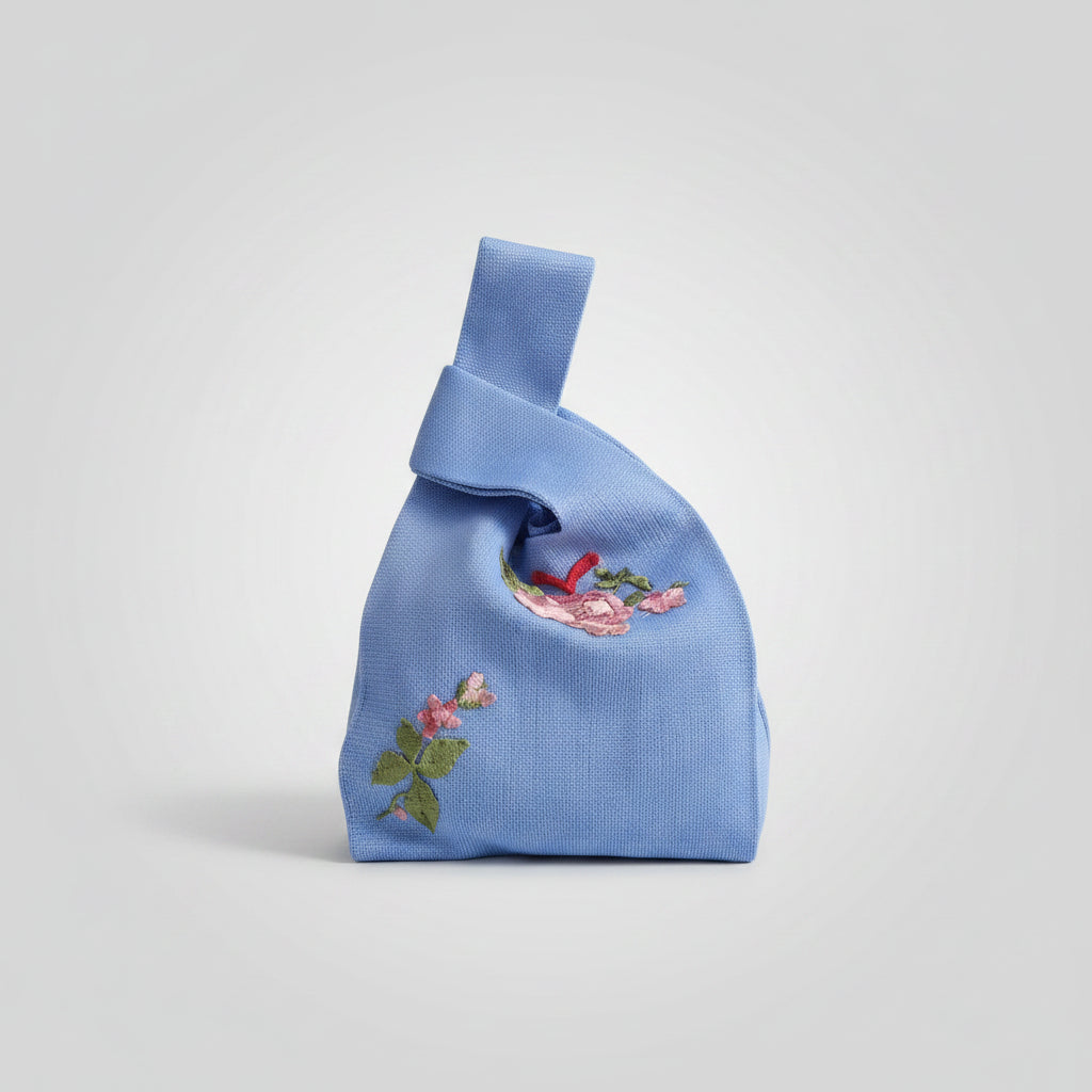 Light blue knot wrist bag with colorful floral embroidery and bird motif