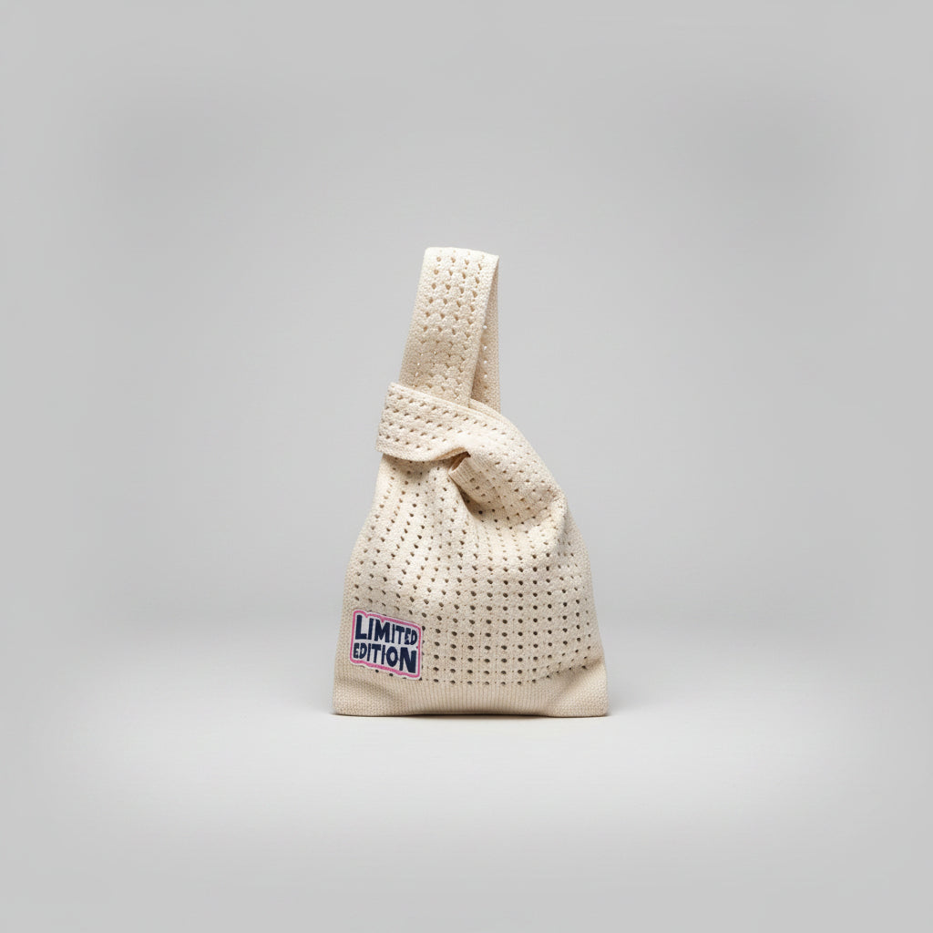 Knot wrist bag in cream with textured weave and “Limited Edition” patch