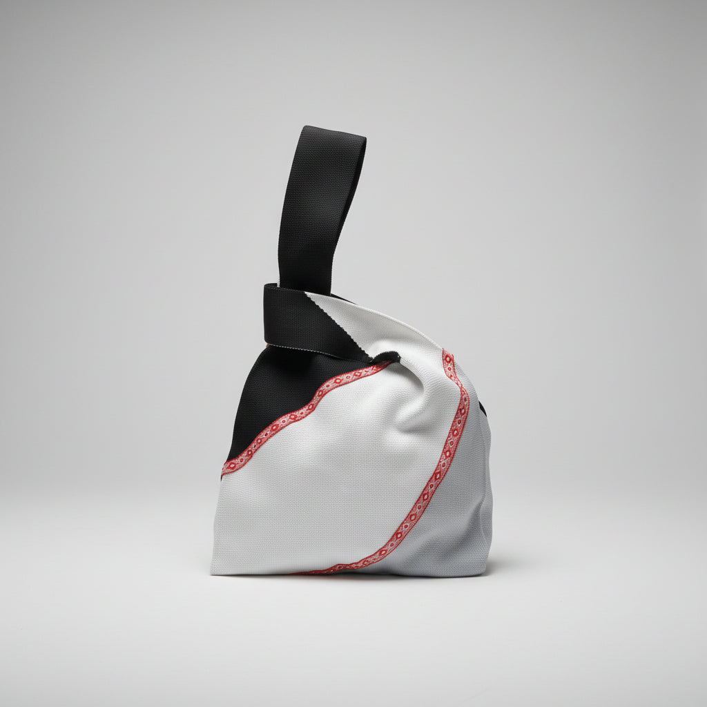 Knot wrist bag in white fabric with red trim and black handle strap.