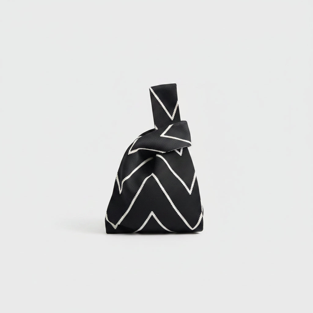 Black knot wrist bag with white chevron line pattern and decorative top loop