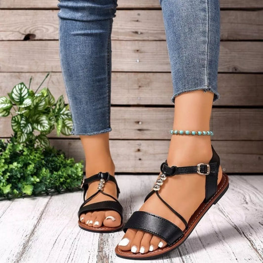 Black open-toe flat sandals with wide ankle strap and silver bead detail