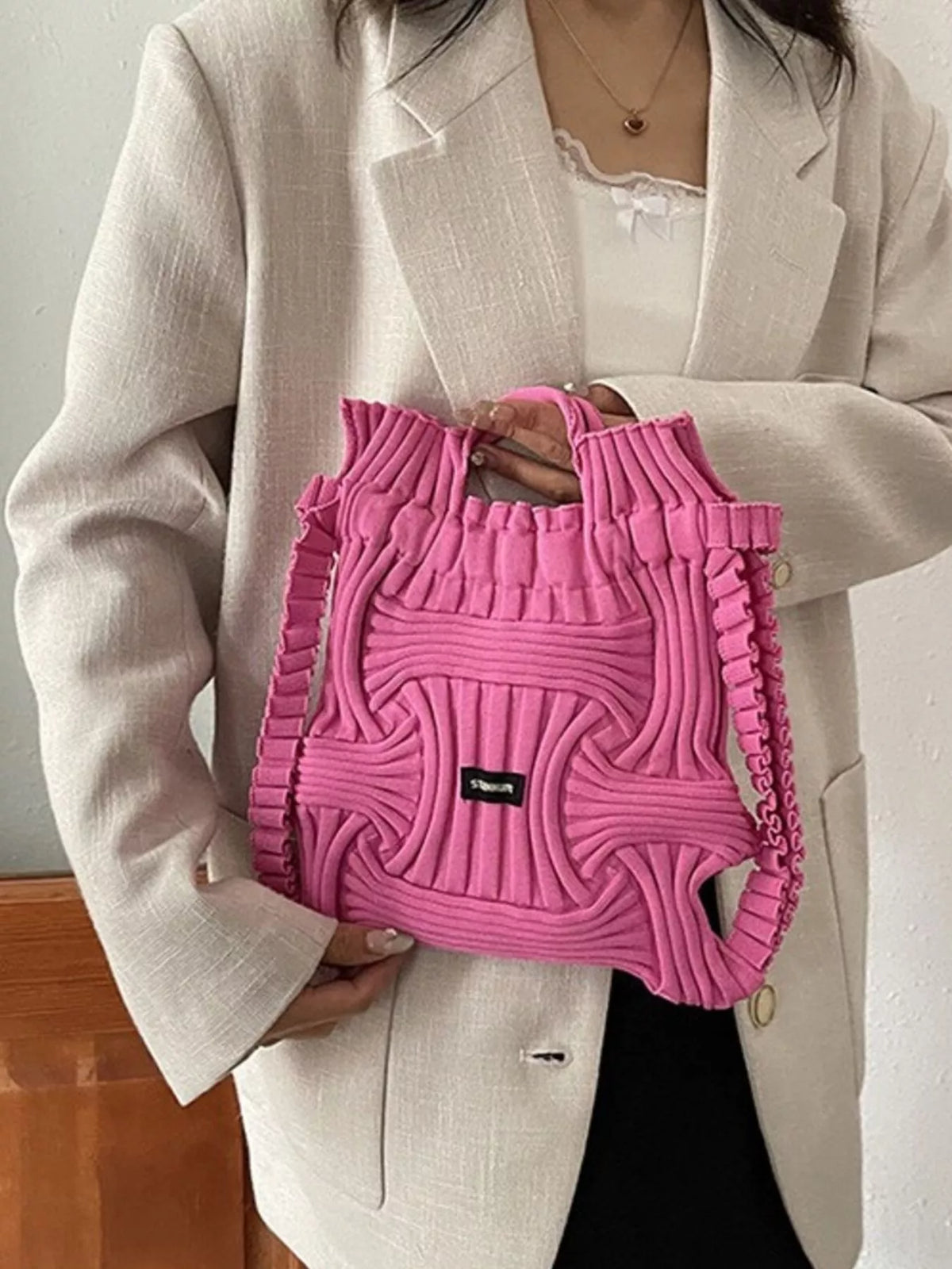 Rose red knitted backpack bag, front view, drawstring top, black logo patch
