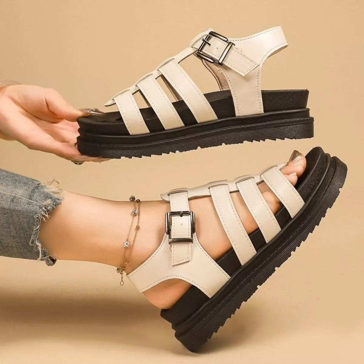 Off-white open-toe platform sandals held by hand; striped straps with buckles