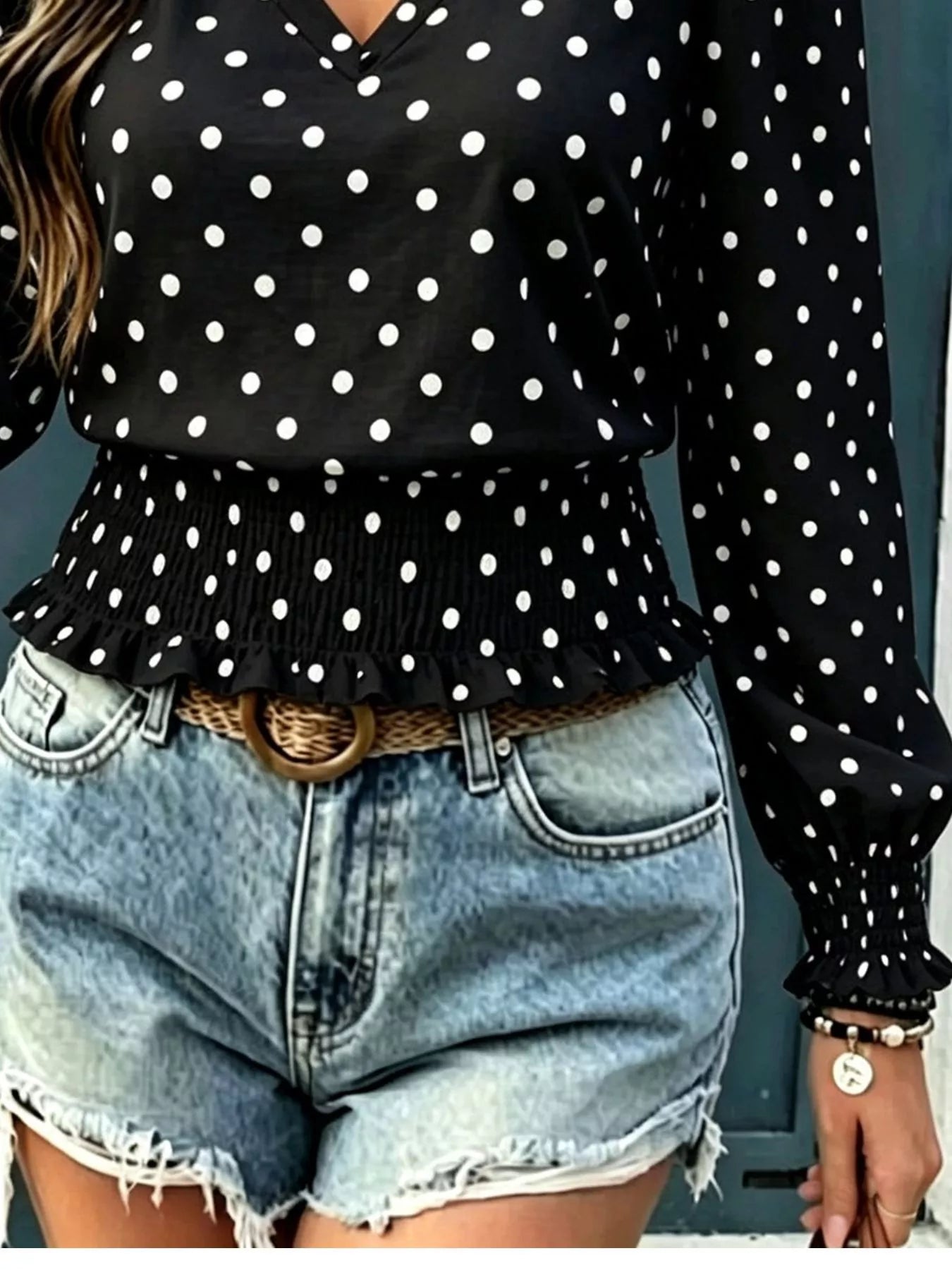Black polka dot V-neck blouse detail with long sleeve smocking and peplum ruffle