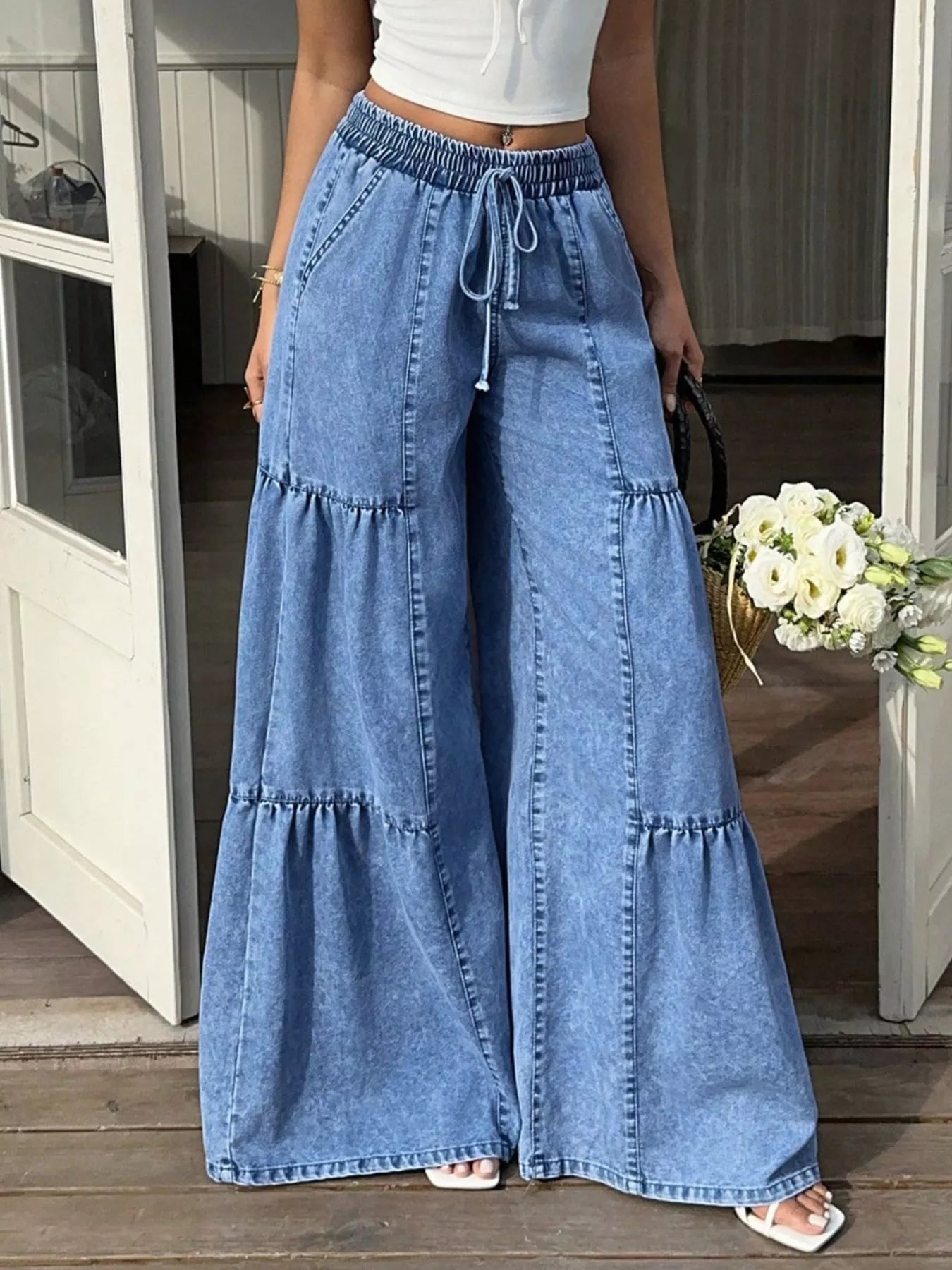 Blue wide-leg tiered denim jeans featuring elastic waist tie and tiered hem
