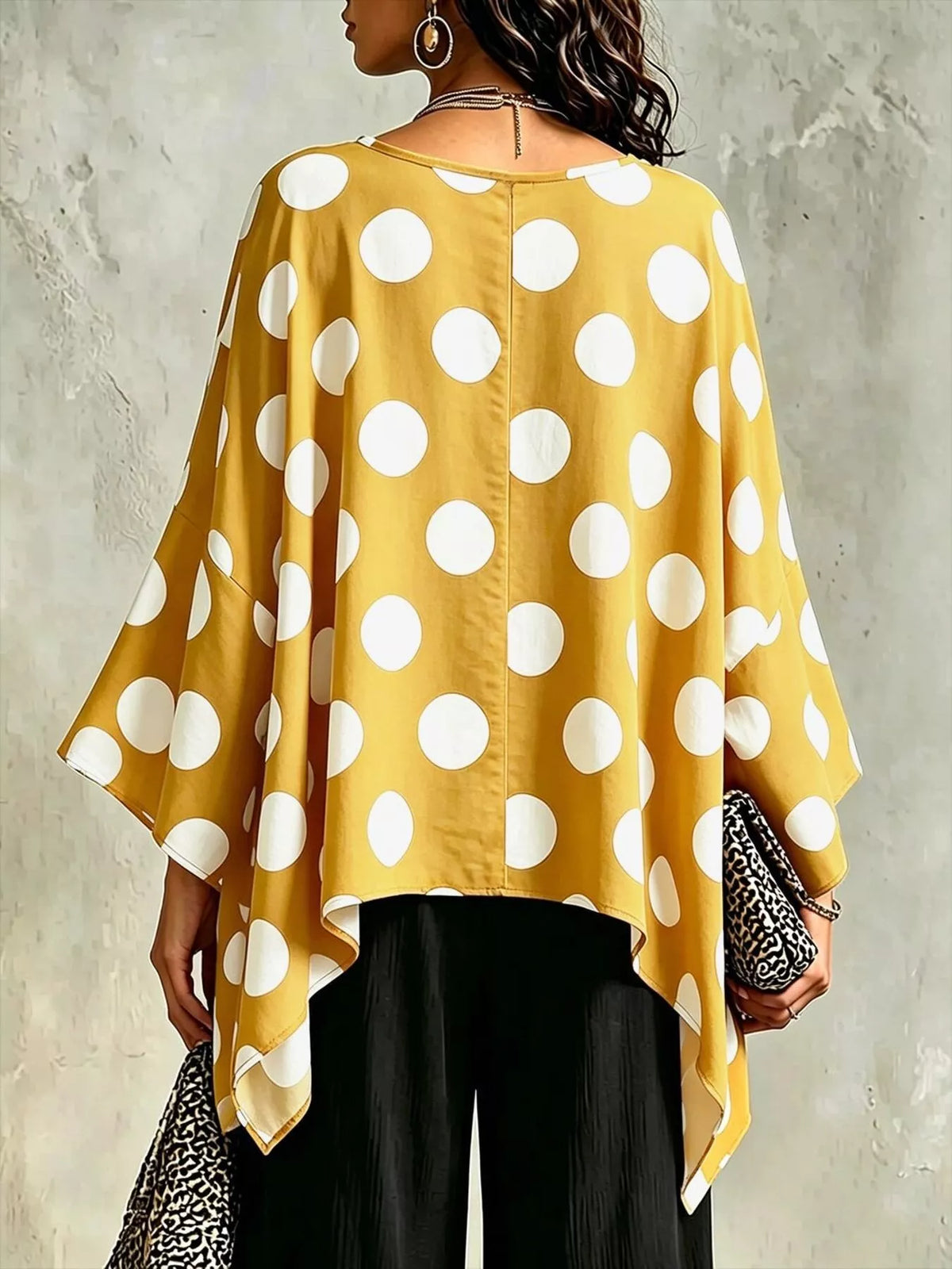 Gold polka dot asymmetrical hem blouse, back view with flowing batwing sleeves.