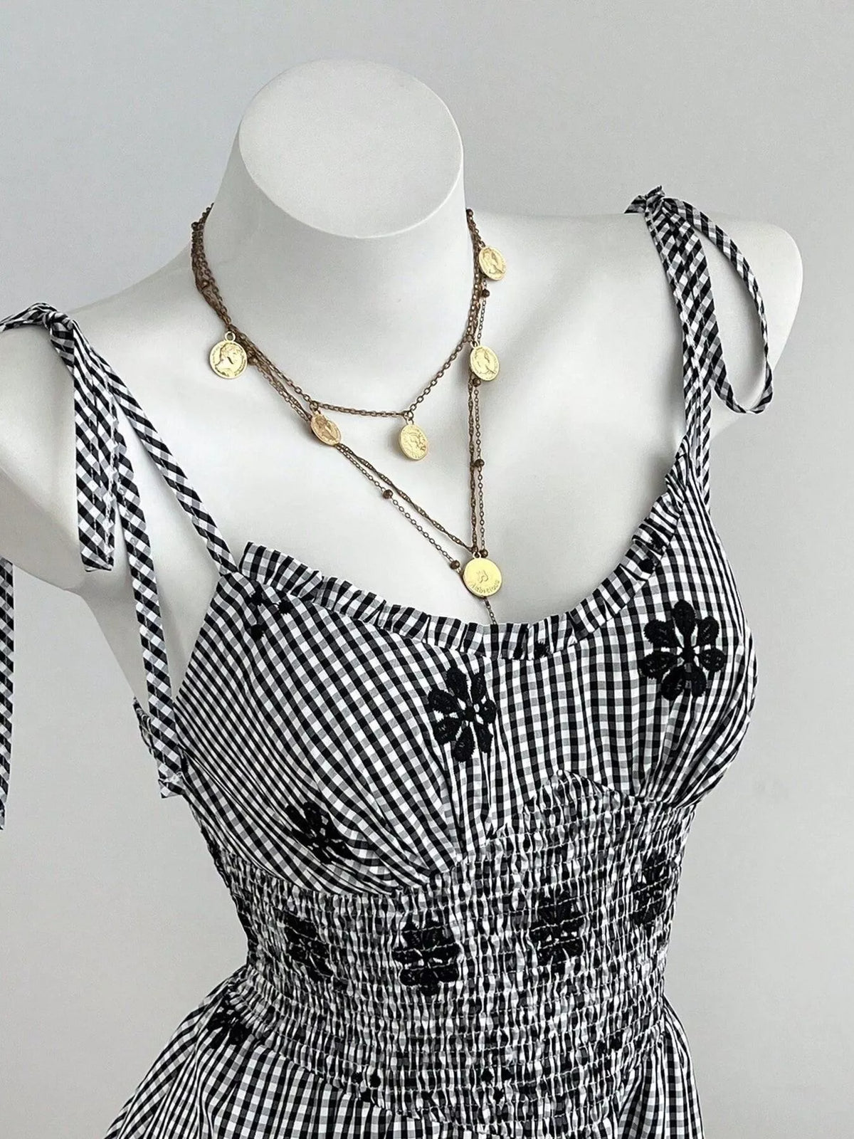 Black-and-white gingham mini dress with floral applique trim and tie straps