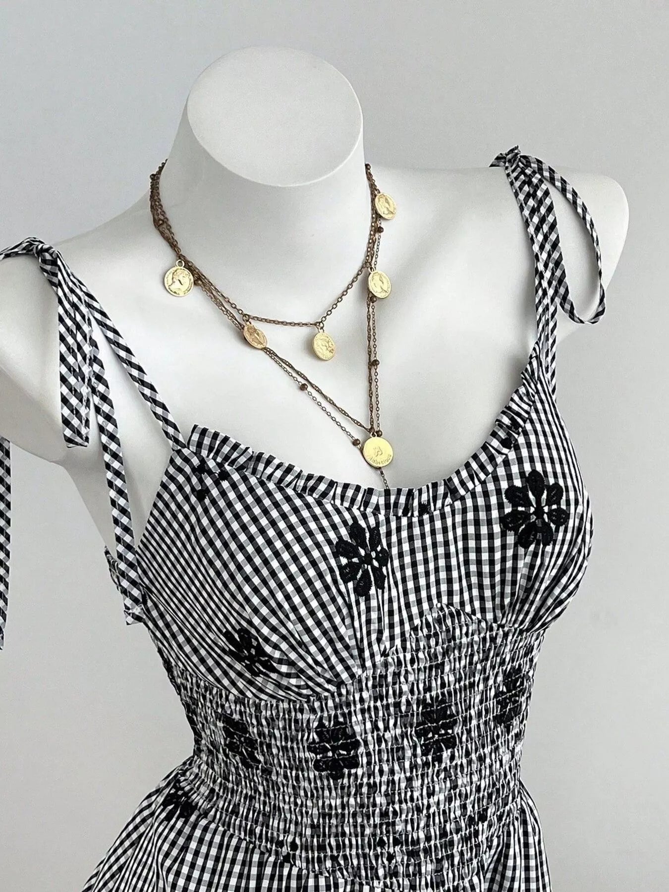Black-and-white gingham mini dress with floral applique trim and tie straps