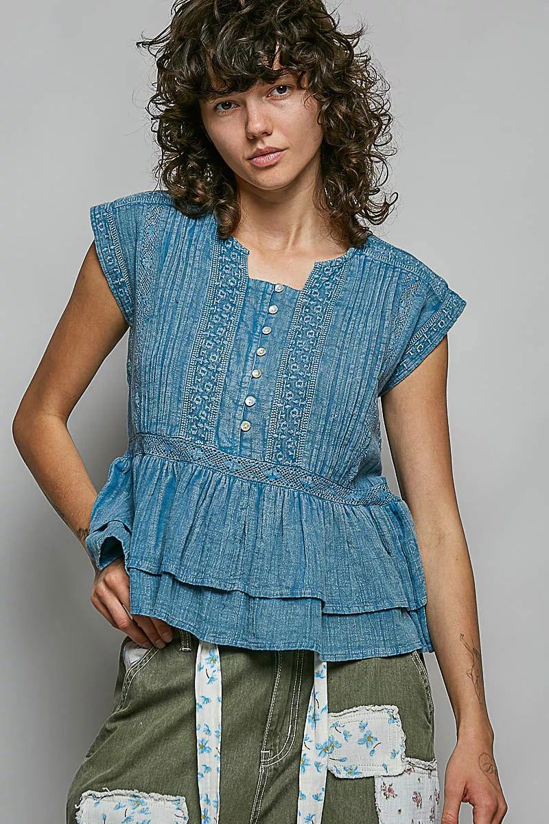 Denim blue sleeveless cotton blouse with pintuck texture, eyelet embroidery, peplum hem