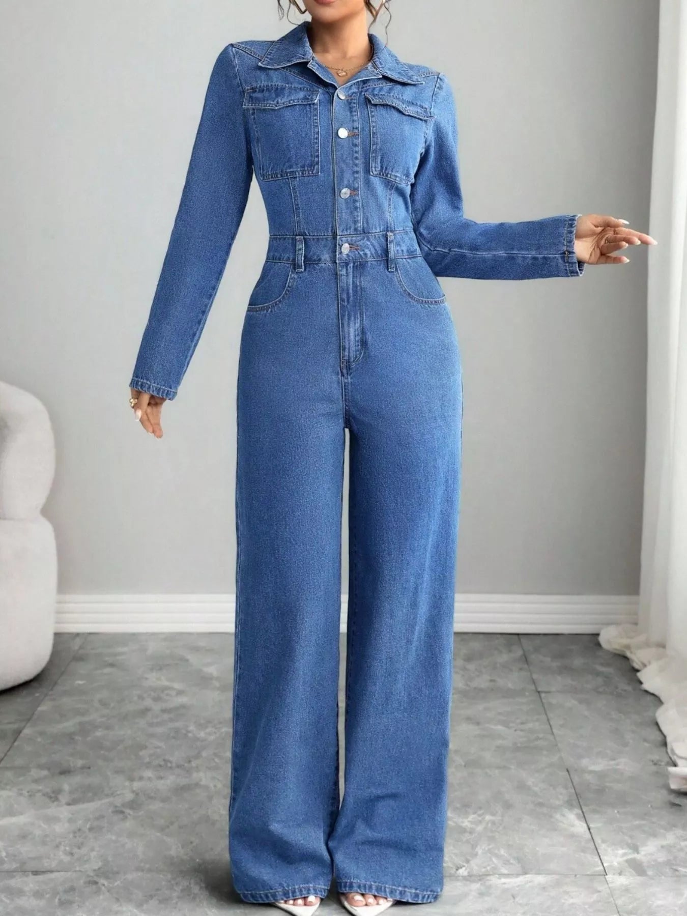 Blue denim button-front long-sleeve jumpsuit with chest pockets, long wide-leg silhouette