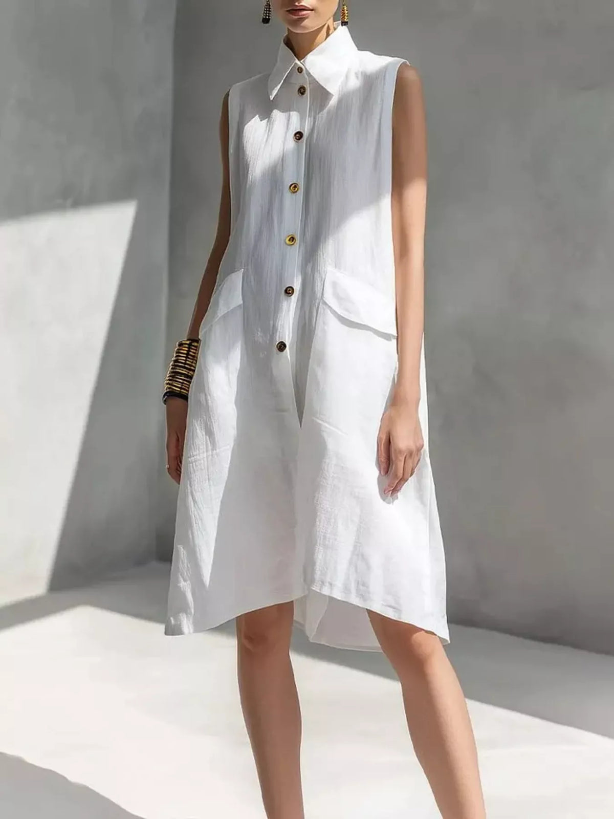 White sleeveless button-front dress with pointed collar and patch pockets, knee length