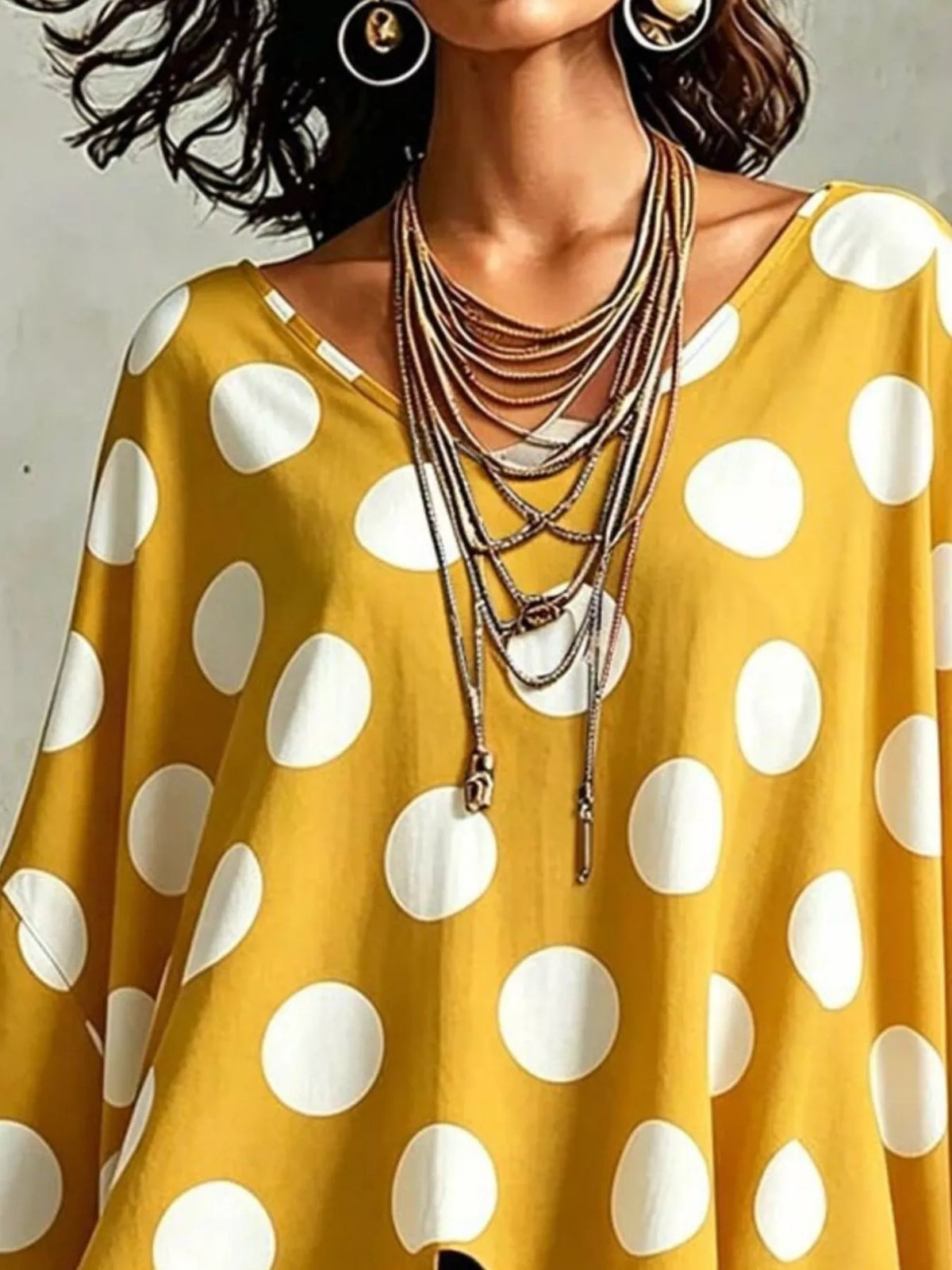 Gold polka dot asymmetrical hem blouse with loose drape and wide round neckline.