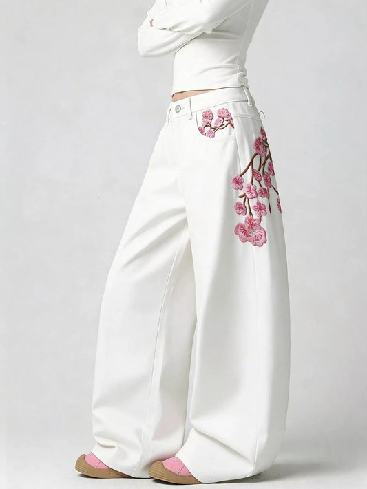 White wide-leg jeans with pink floral embroidery along side seam, button waist