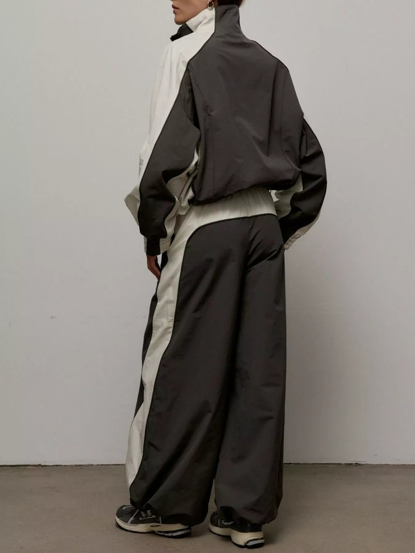 Color-block zip-up jacket and wide-leg pants set, black outer with light panel accents.