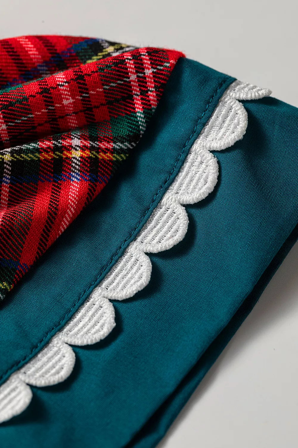 Teal trim with white scalloped embroidery on deep red plaid shift blouse