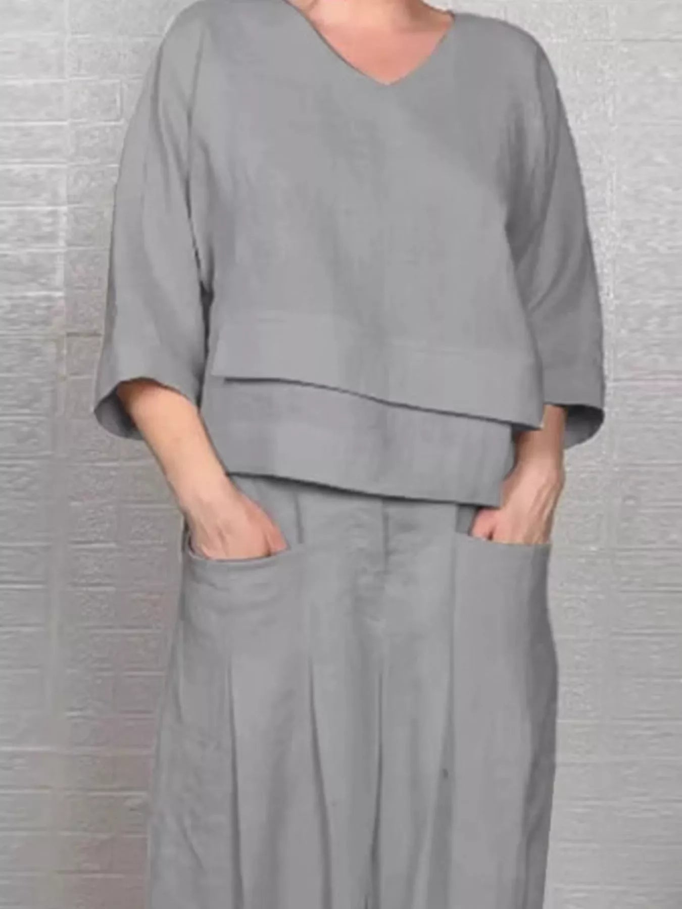 Grey V-neck long sleeve top and wide-leg pants set, front view with draped overlay hem.