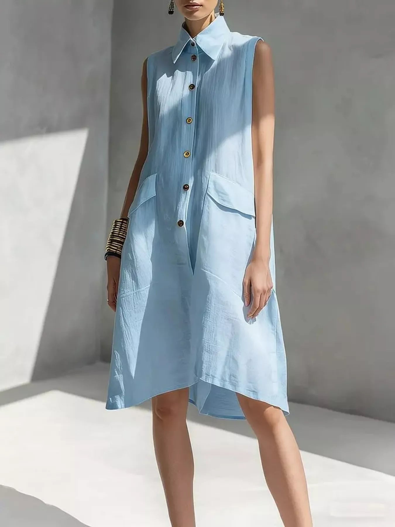Light blue sleeveless button-front dress with pointed collar and patch pockets, knee length