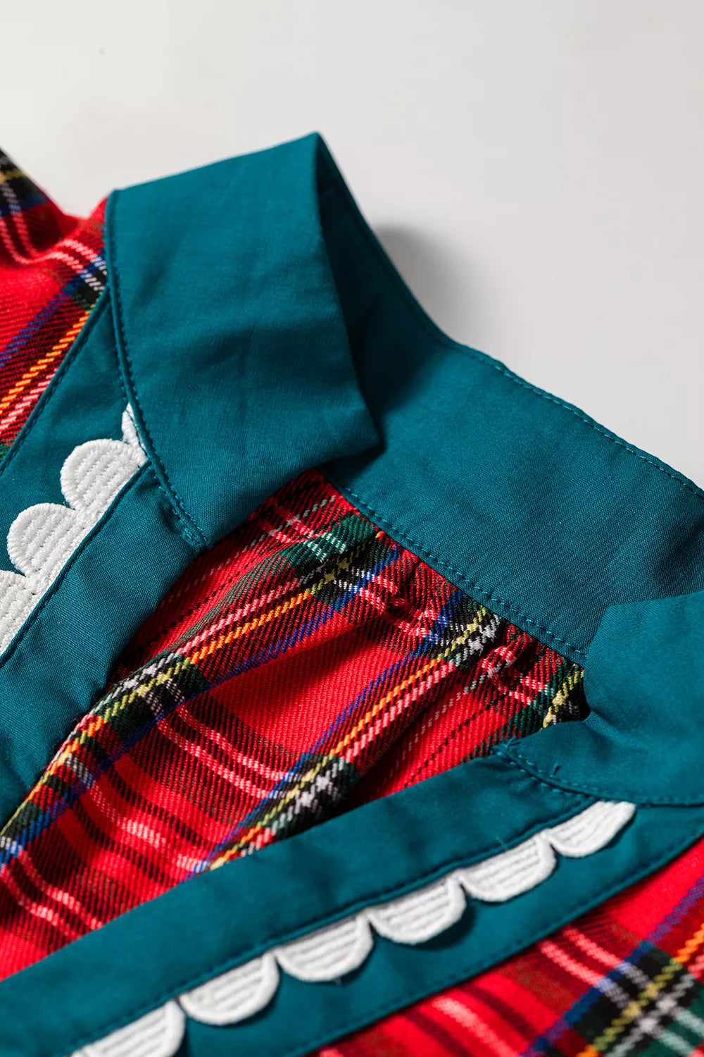 Teal V-neck facing on deep red plaid shift blouse with white scalloped edge