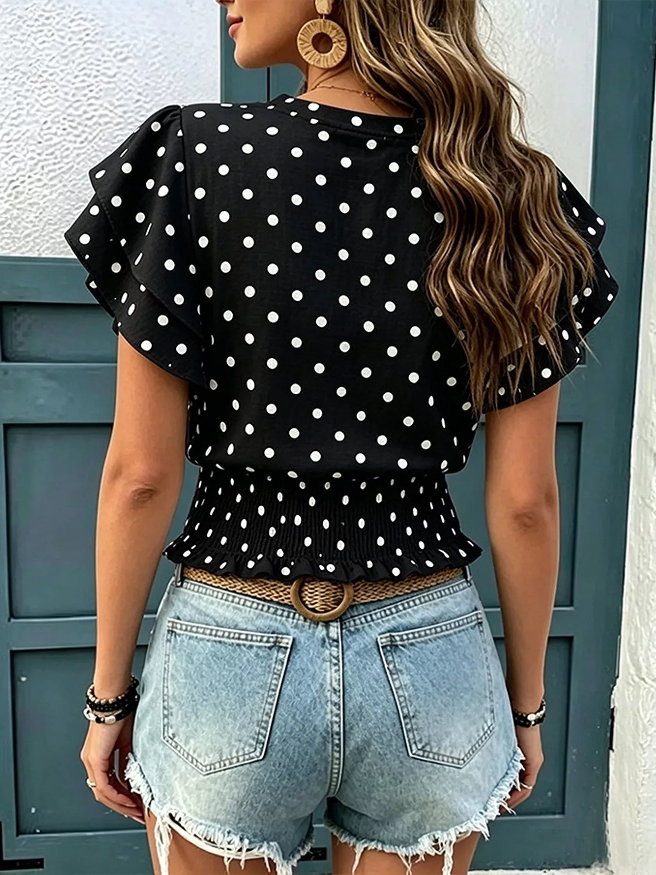 Black polka dot blouse with flutter sleeves and gathered peplum detail
