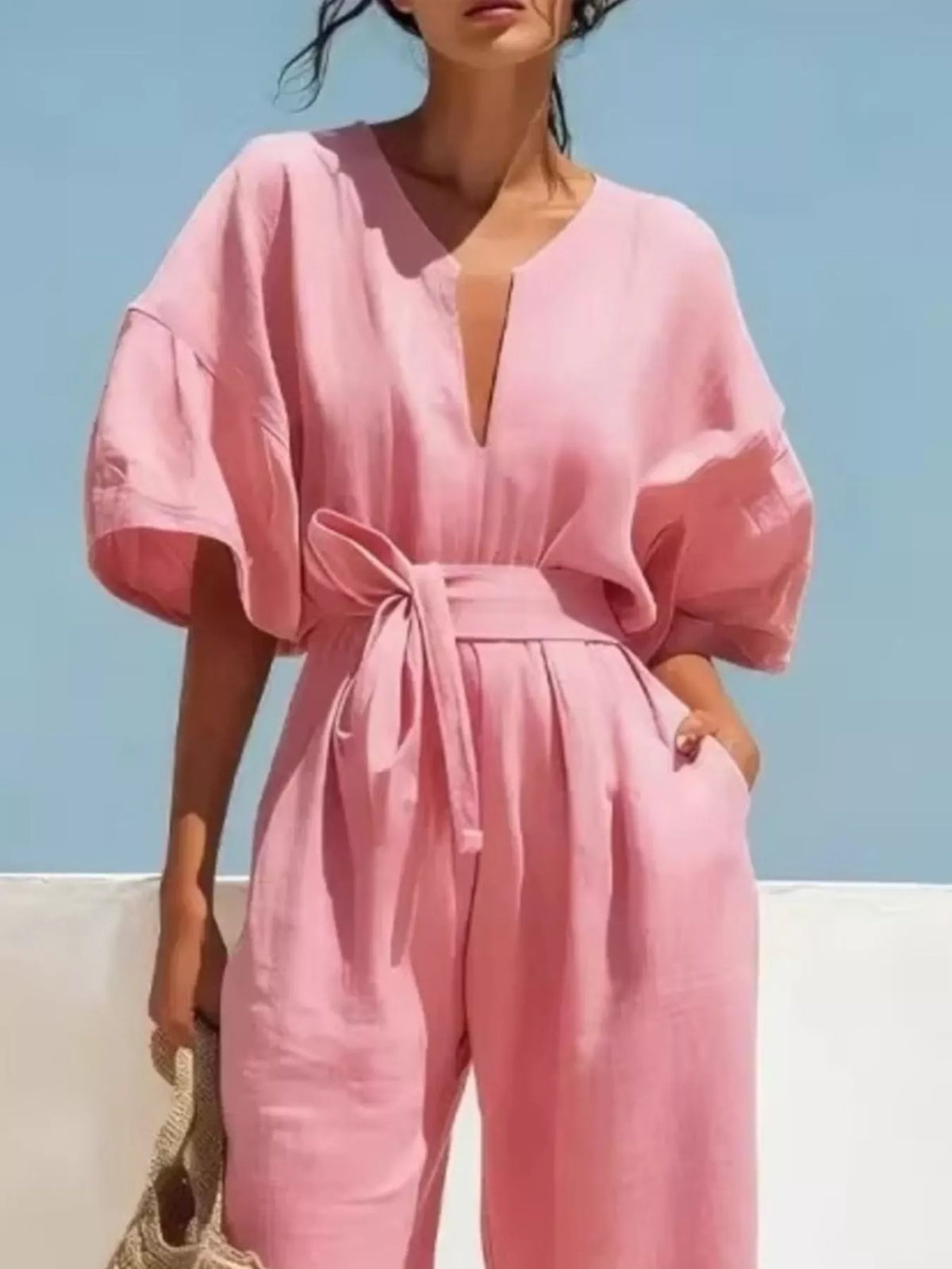 Pink tie-waist wide-leg jumpsuit with V-neck, belted waist tie, and puff sleeves