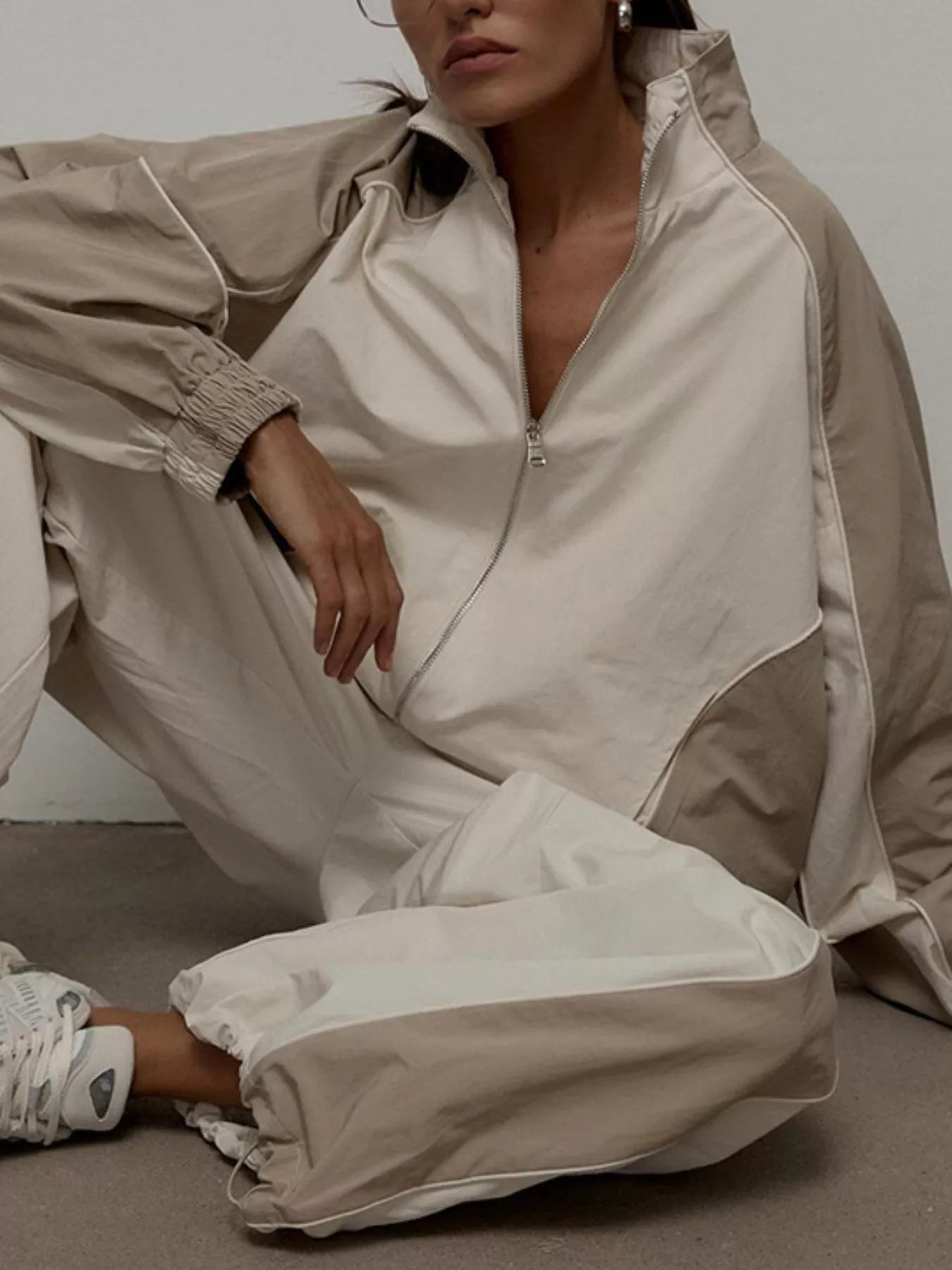 Light beige/cream zip-up jacket with contrast side panels, matching relaxed pants set.