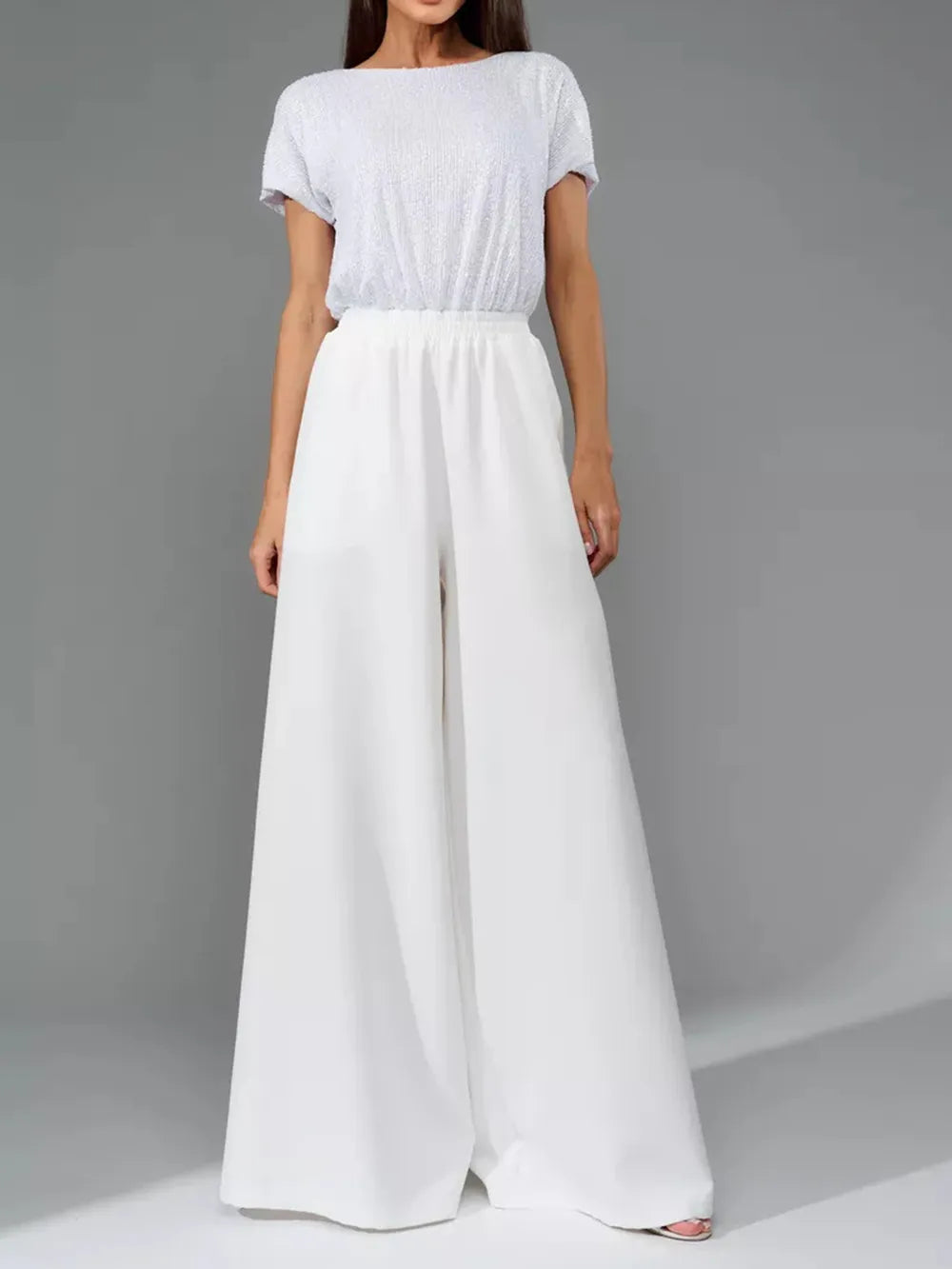 White wide-leg jumpsuit with round neck, short sleeves, and gathered waist.