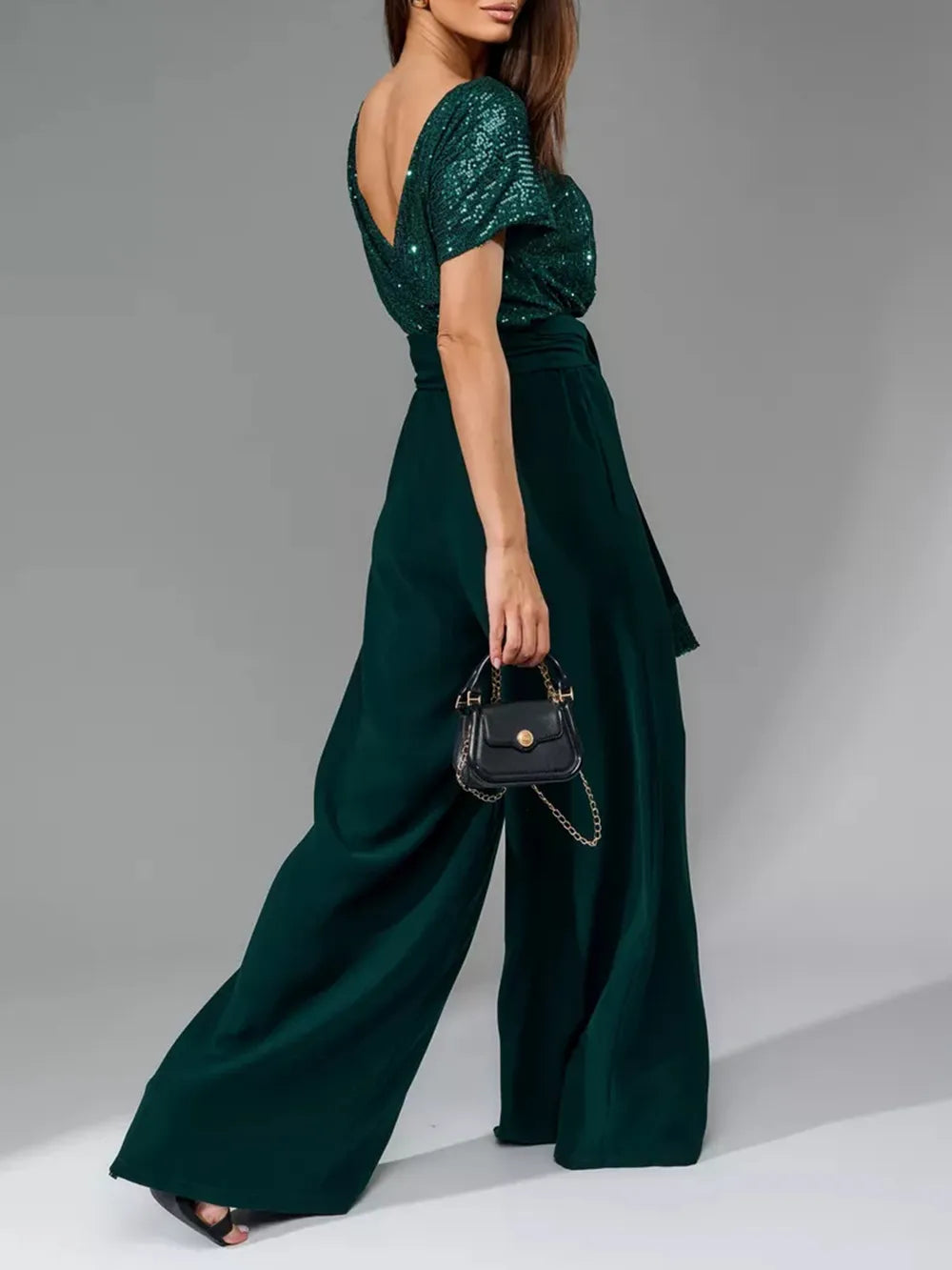 Side view of dark green sequin wide-leg jumpsuit with short sleeves and belt