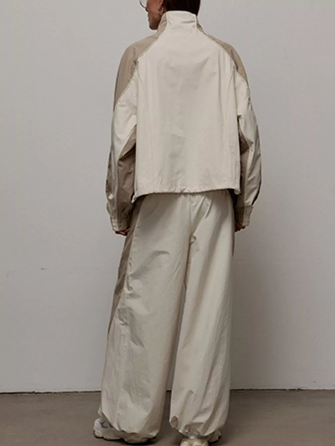 Back view of light beige/cream zip-up jacket and wide-leg pants set, color-block panels.