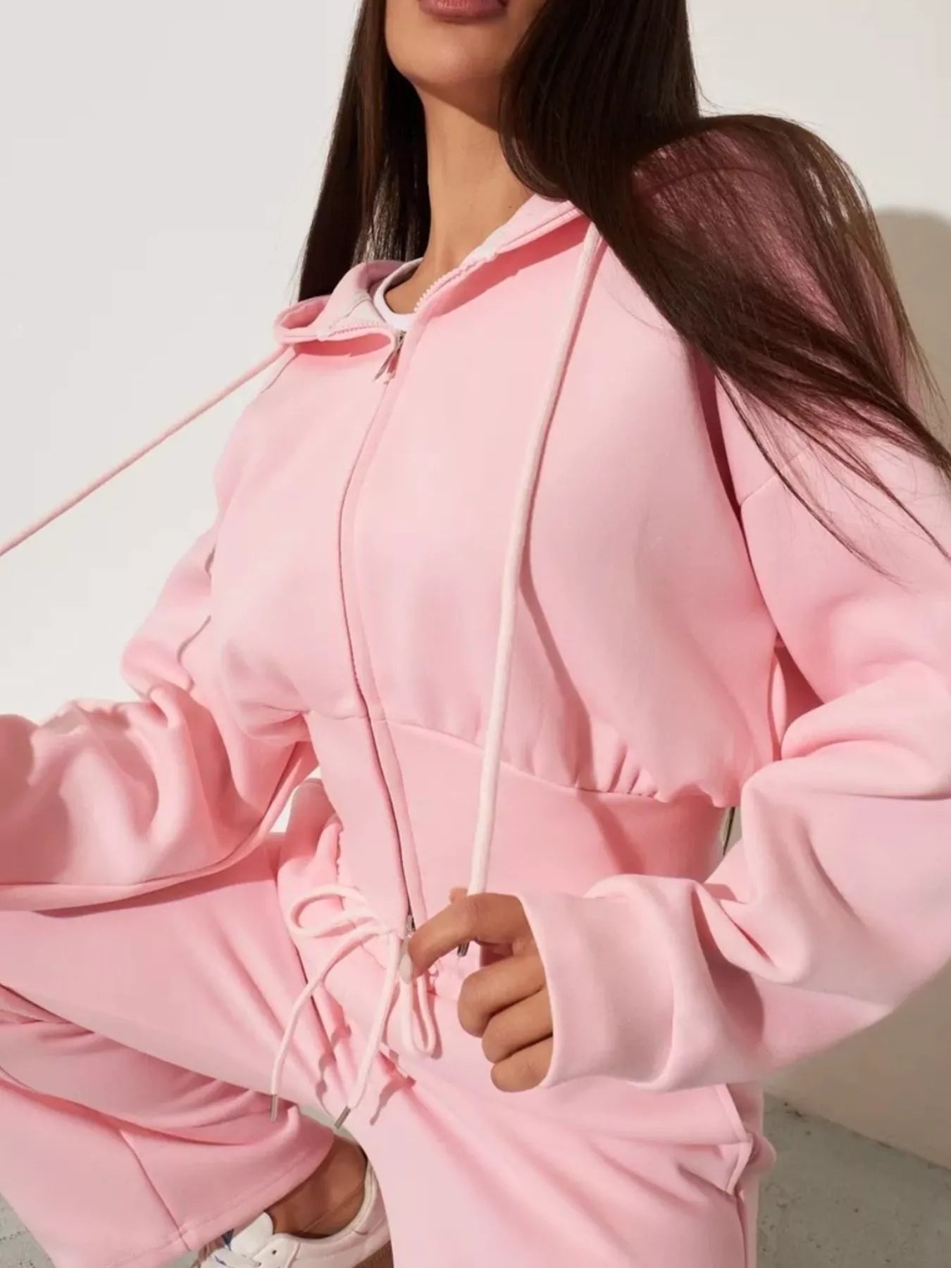 Pink zip-up hoodie and wide-leg pants set with hood and front zipper, close-up view
