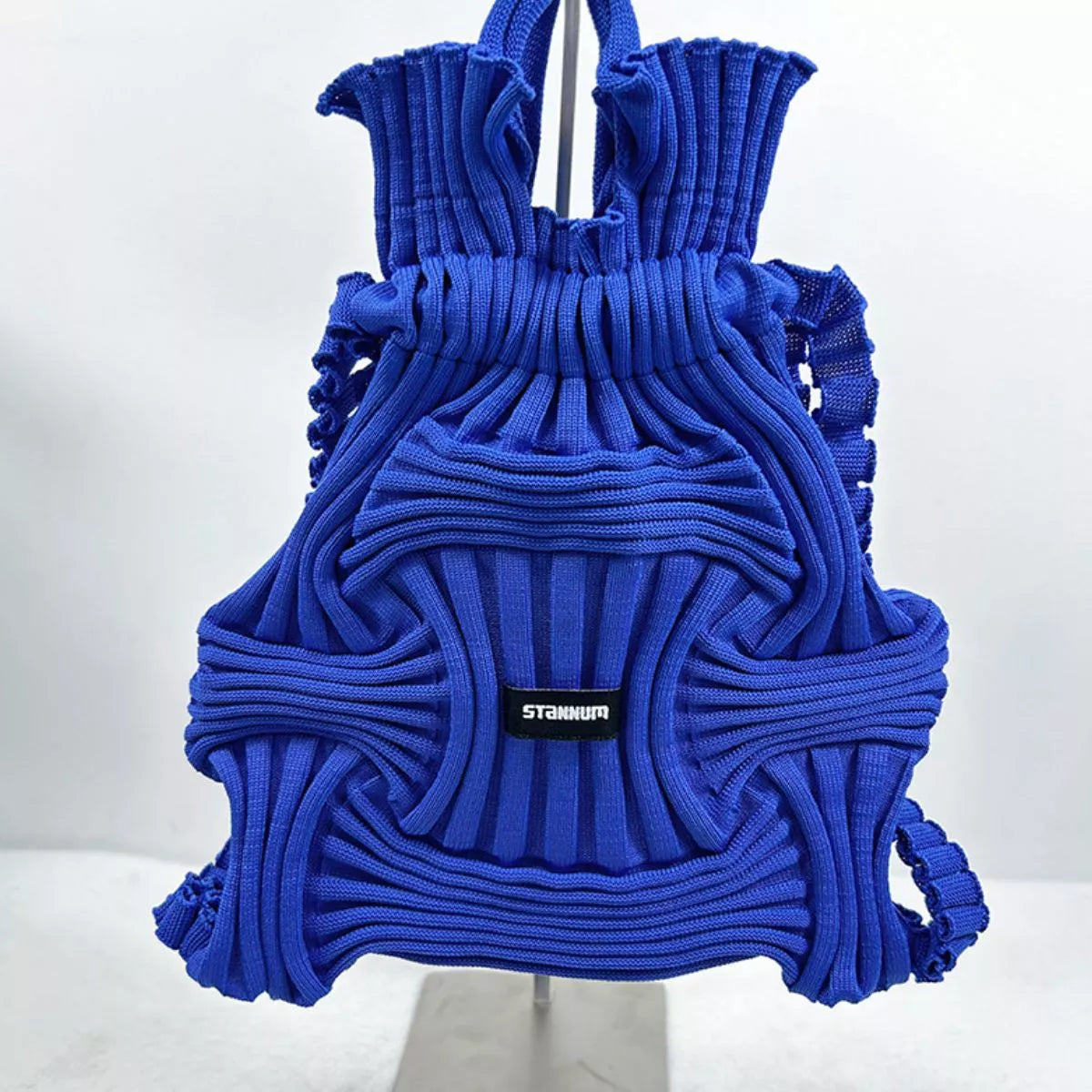 Royal blue textured knit backpack with ruffled body, top handles, front patch logo