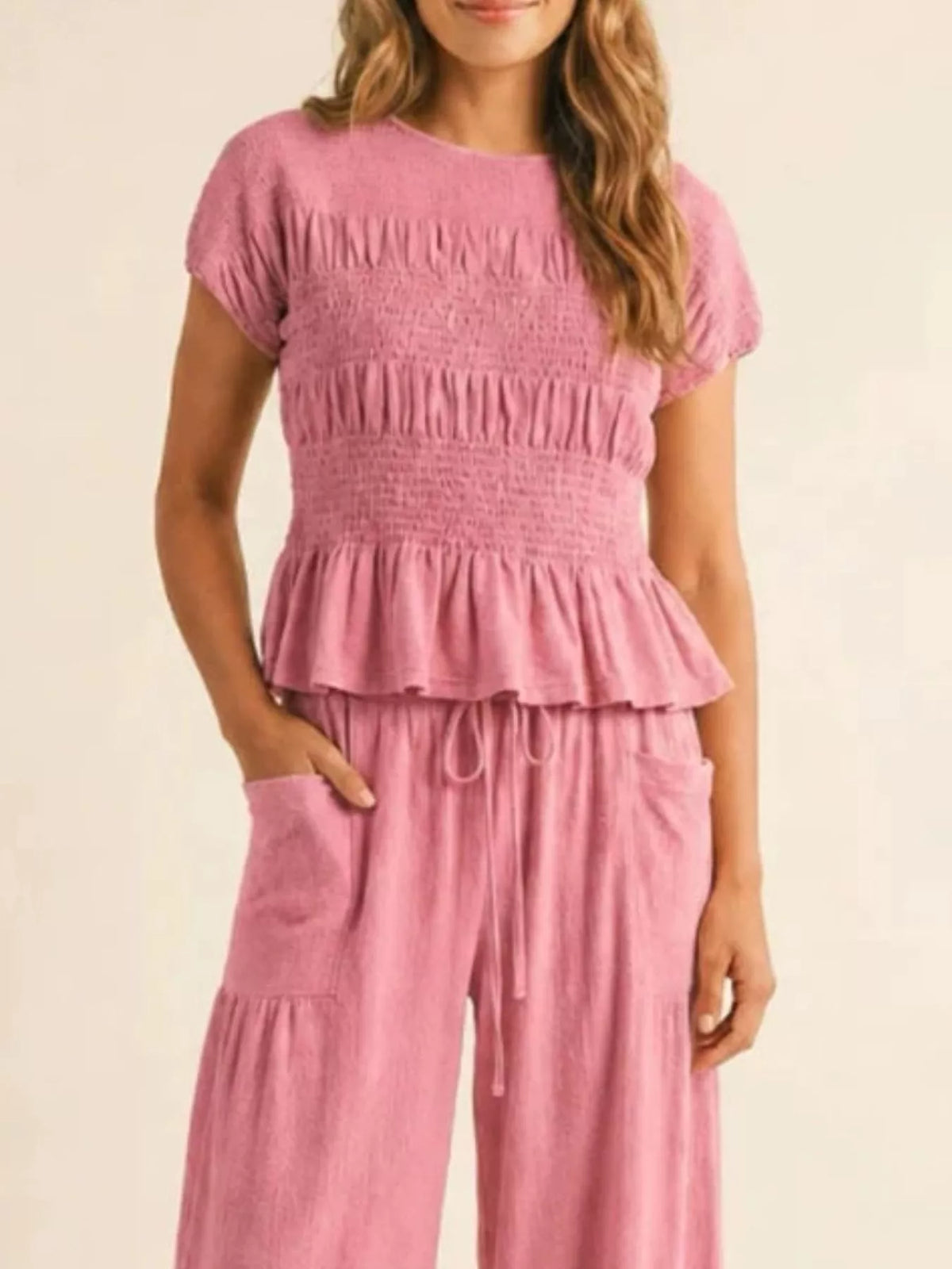 Pink smocked peplum top and wide-leg pants set with ruffled tier detail and drawstring tie