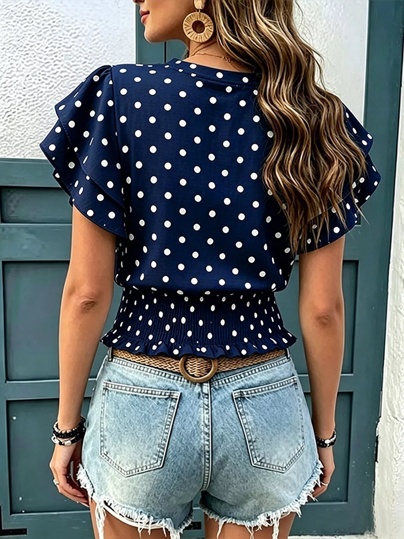 Navy polka dot blouse with ruffle sleeves and gathered waist, peplum hem