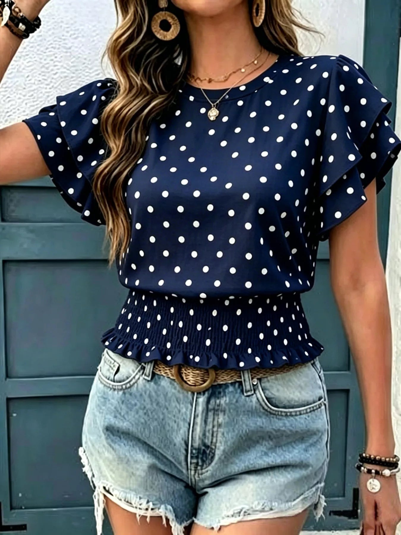Navy polka dot blouse with flutter ruffle sleeves and peplum hem