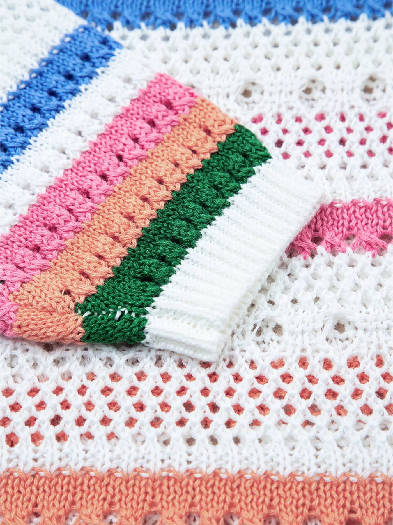 White pointelle knit sweater sleeve cuff with orange, pink, green, and blue stripes