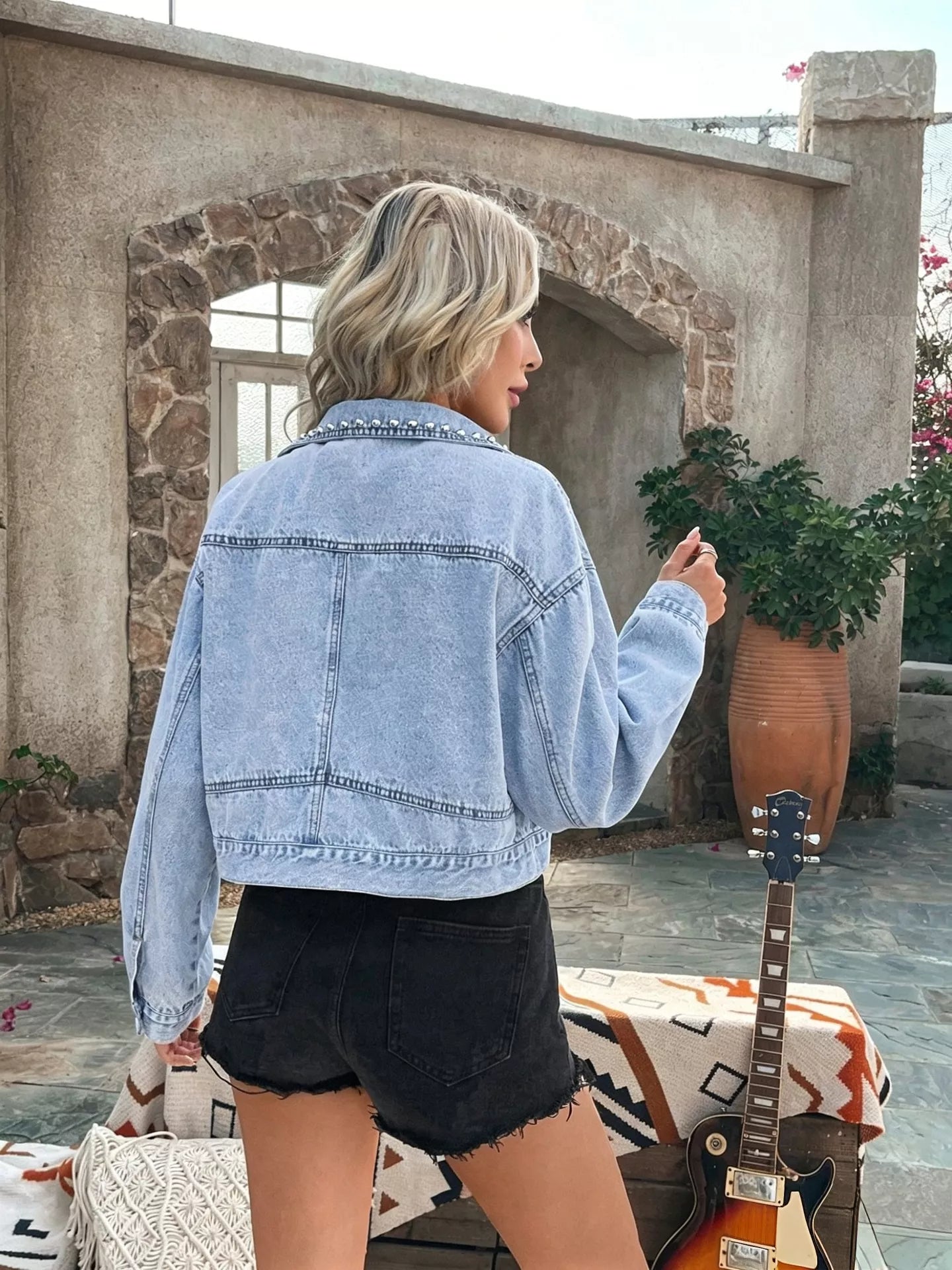 Light-wash blue denim jacket back with studded yoke detail and long sleeves