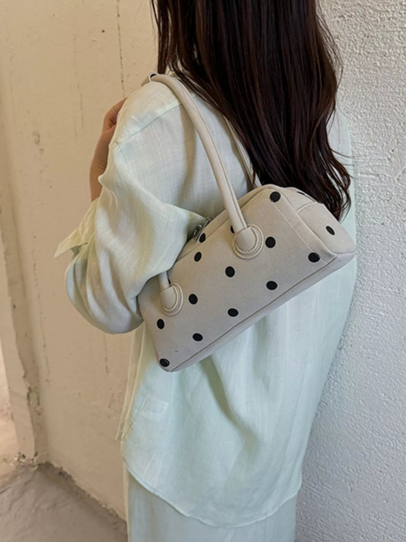 Off-white polka dot shoulder bag held at the side with top handles