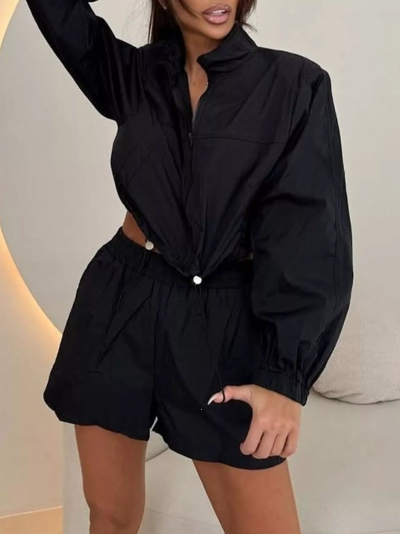 Black zip-up long sleeve jacket with matching shorts, elastic waistband, side view